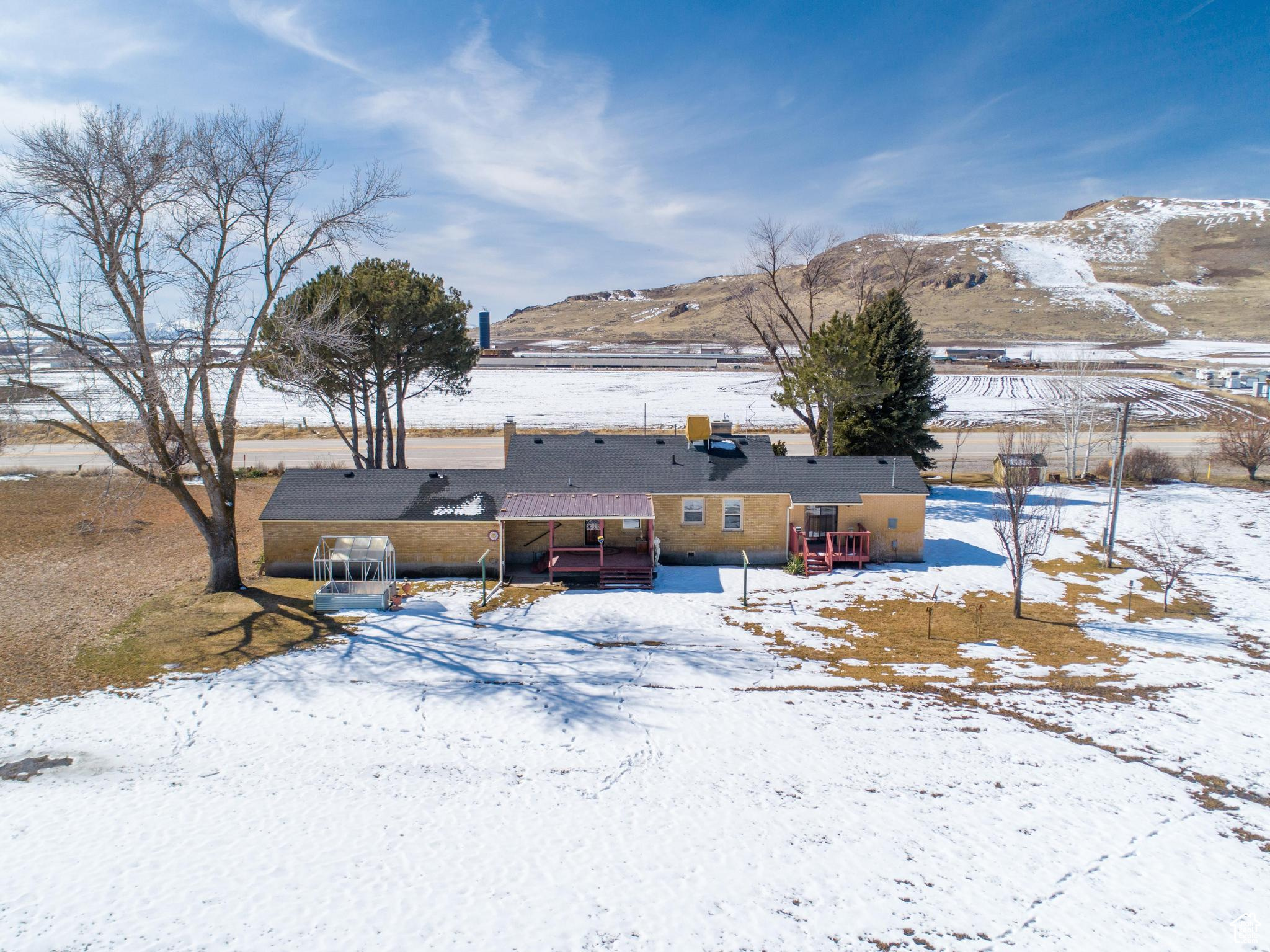 Snow covered back of property with a mountain view
