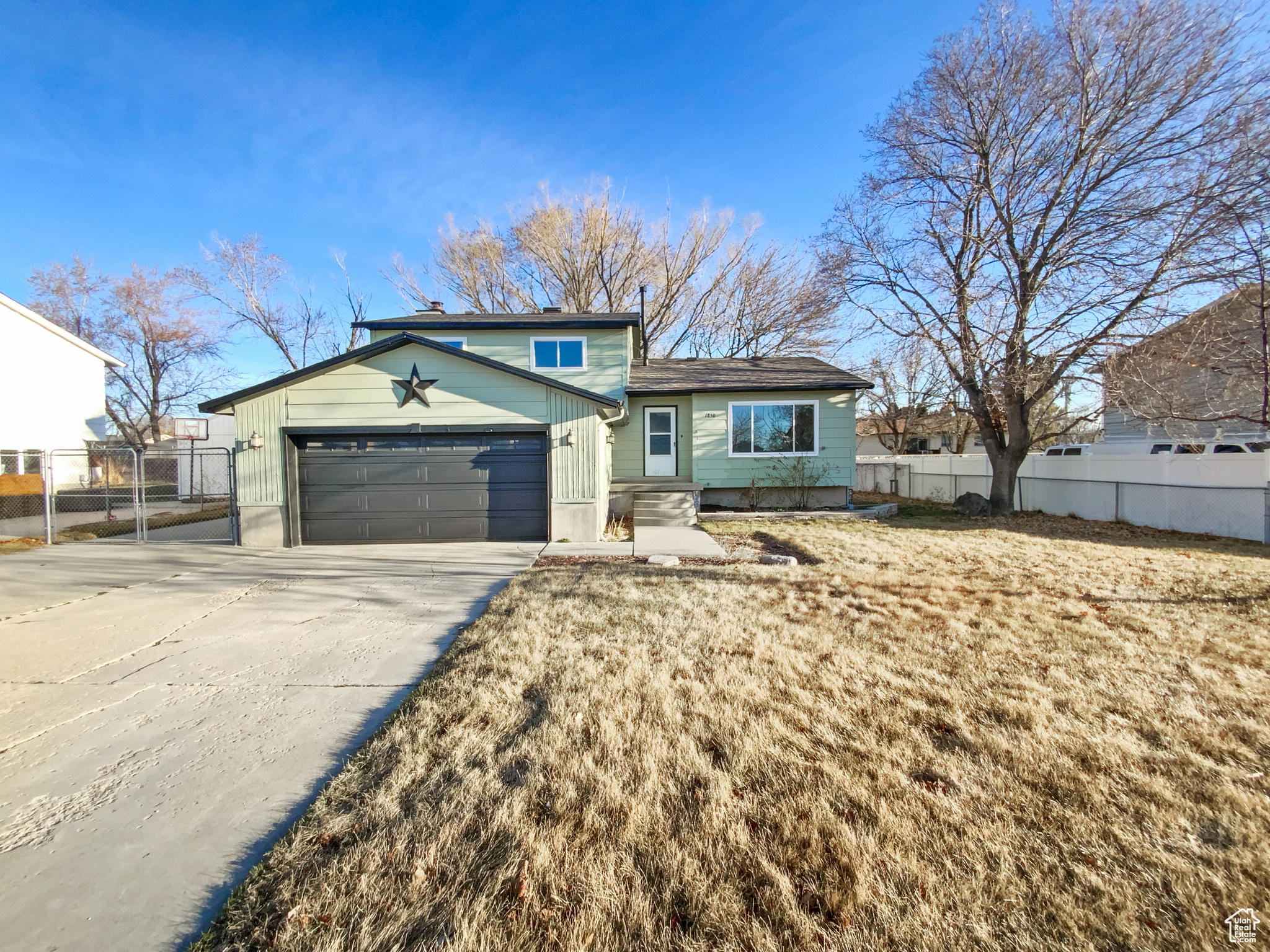 View of front of house with a garage, concrete driveway, and fence