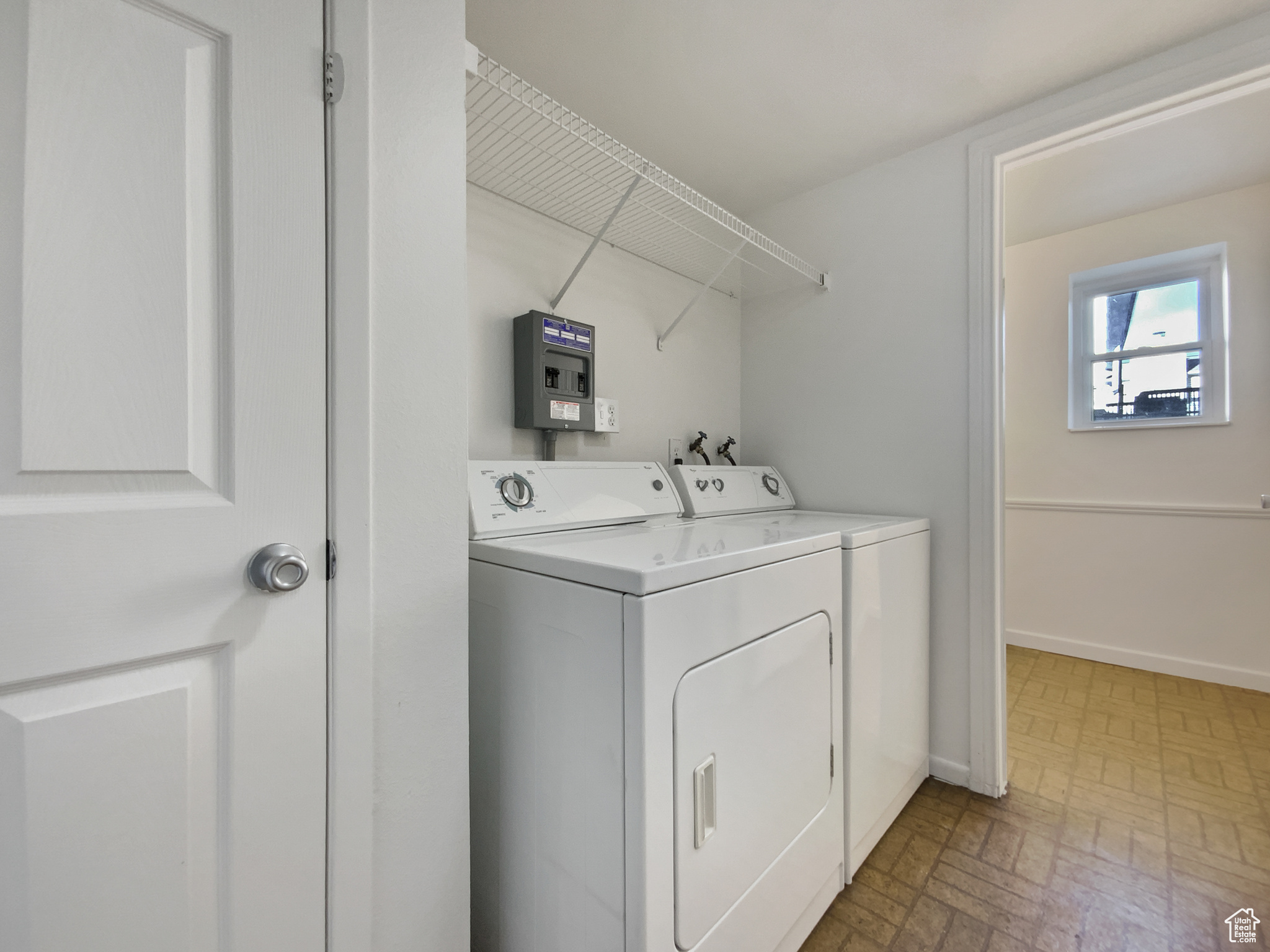 Clothes washing area featuring laundry area, washing machine and dryer, brick floor, and baseboards