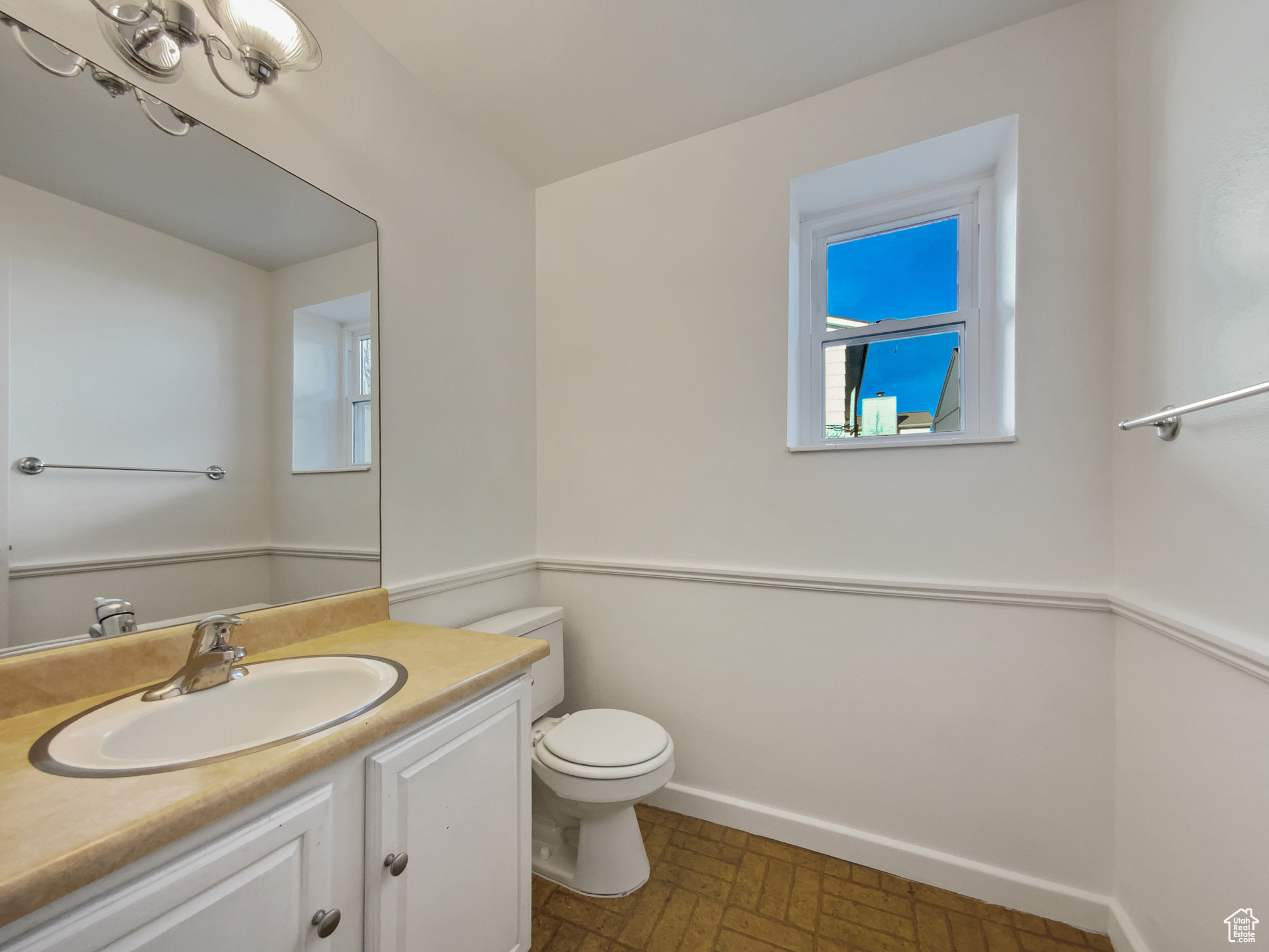 Half bathroom with toilet, vanity, and baseboards