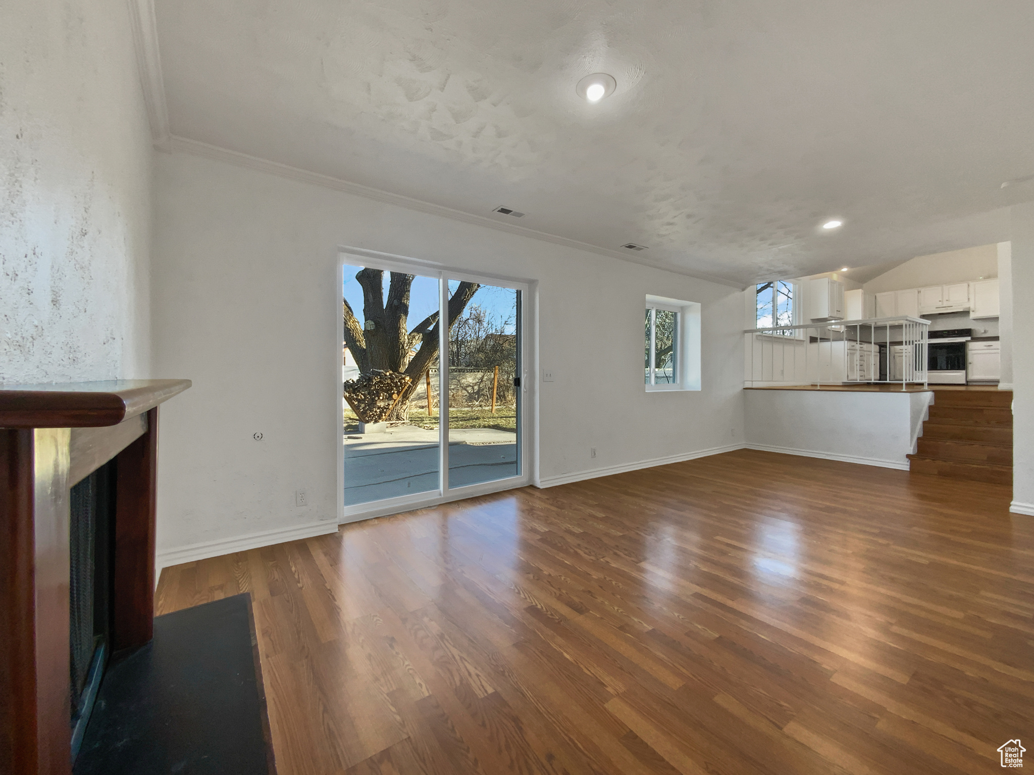 Unfurnished living room featuring baseboards, a fireplace with flush hearth, visible vents, and dark wood-style floors