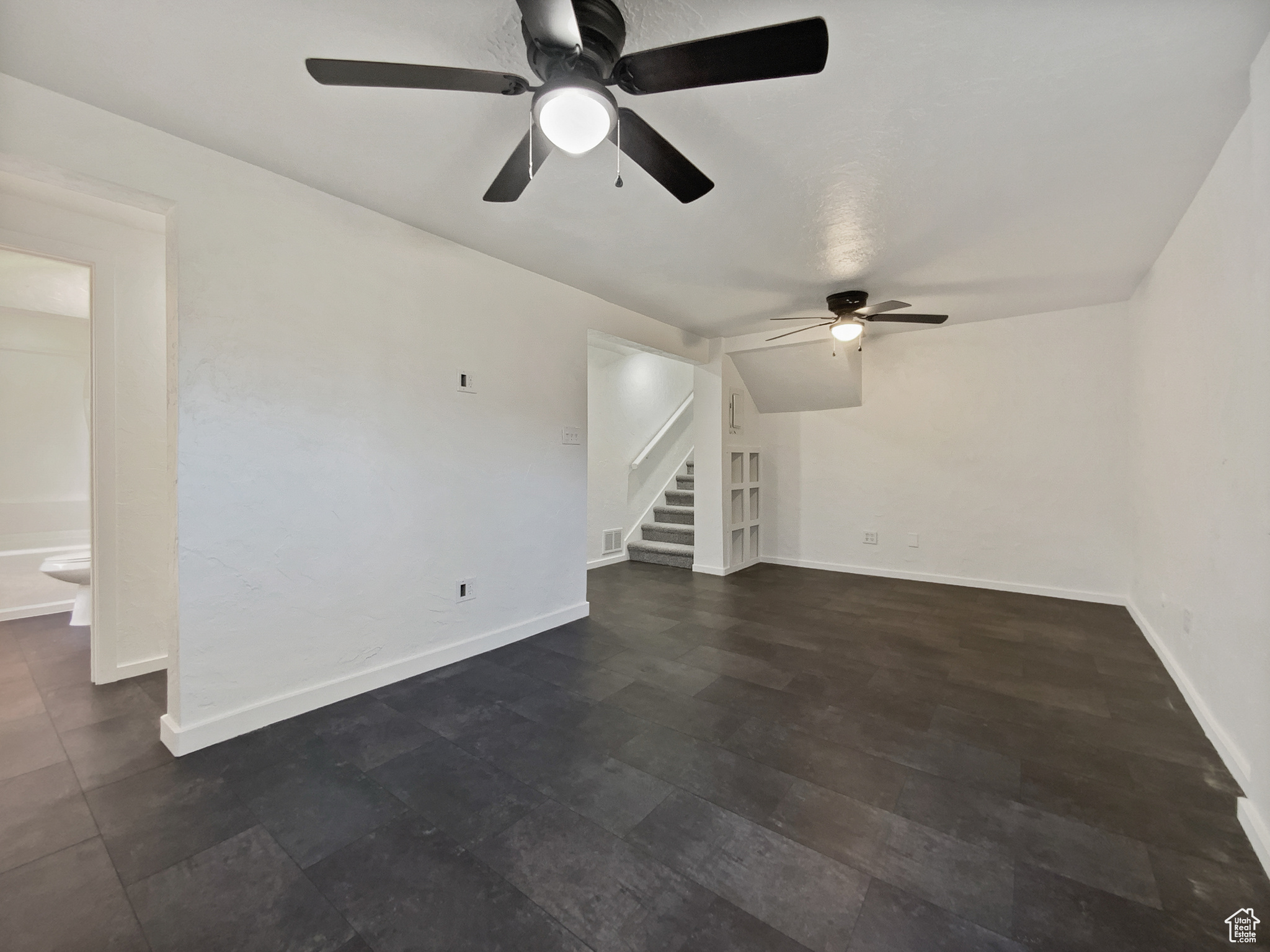 Unfurnished living room featuring stairs and baseboards
