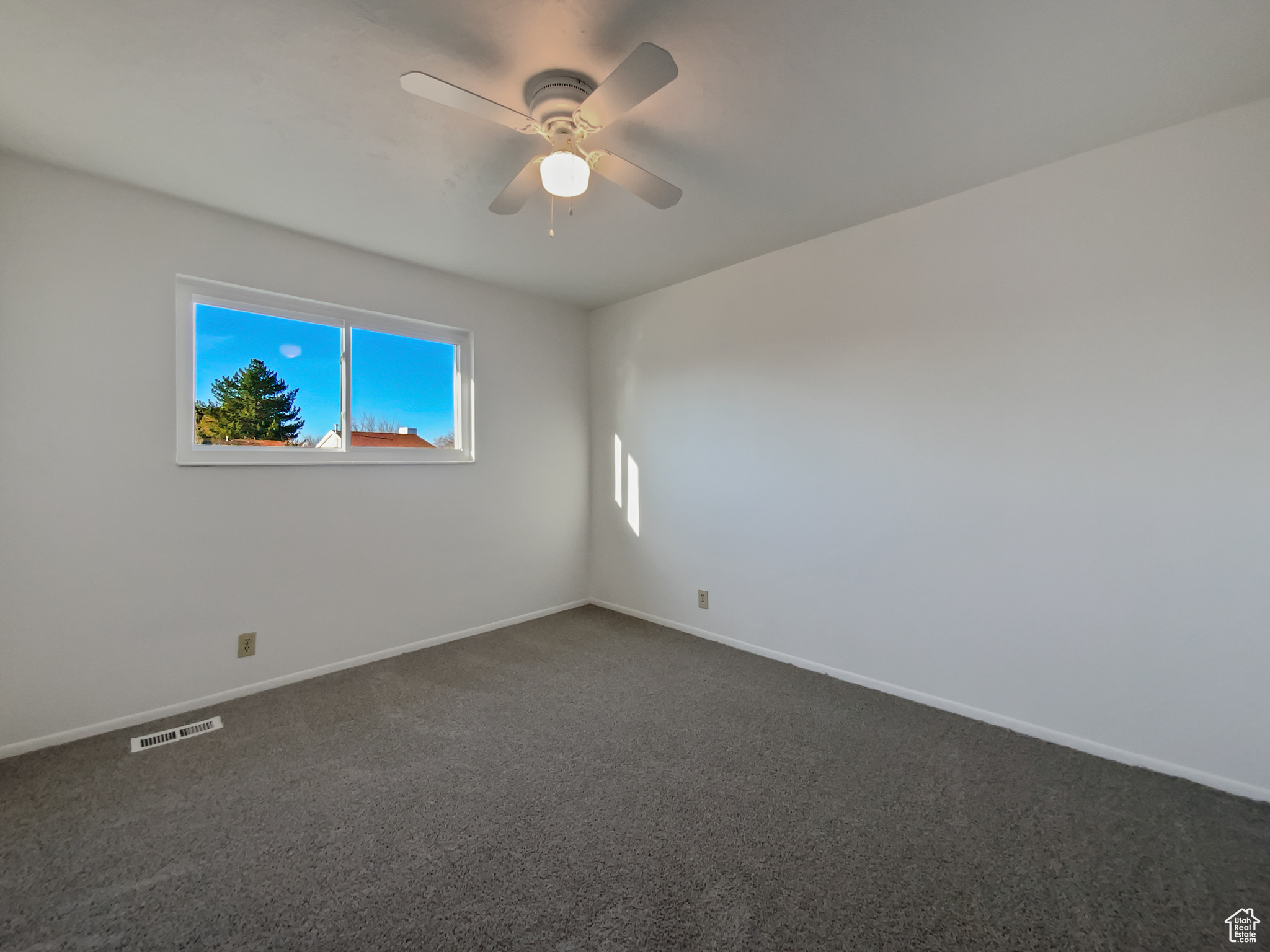 Empty room with visible vents, baseboards, and dark carpet