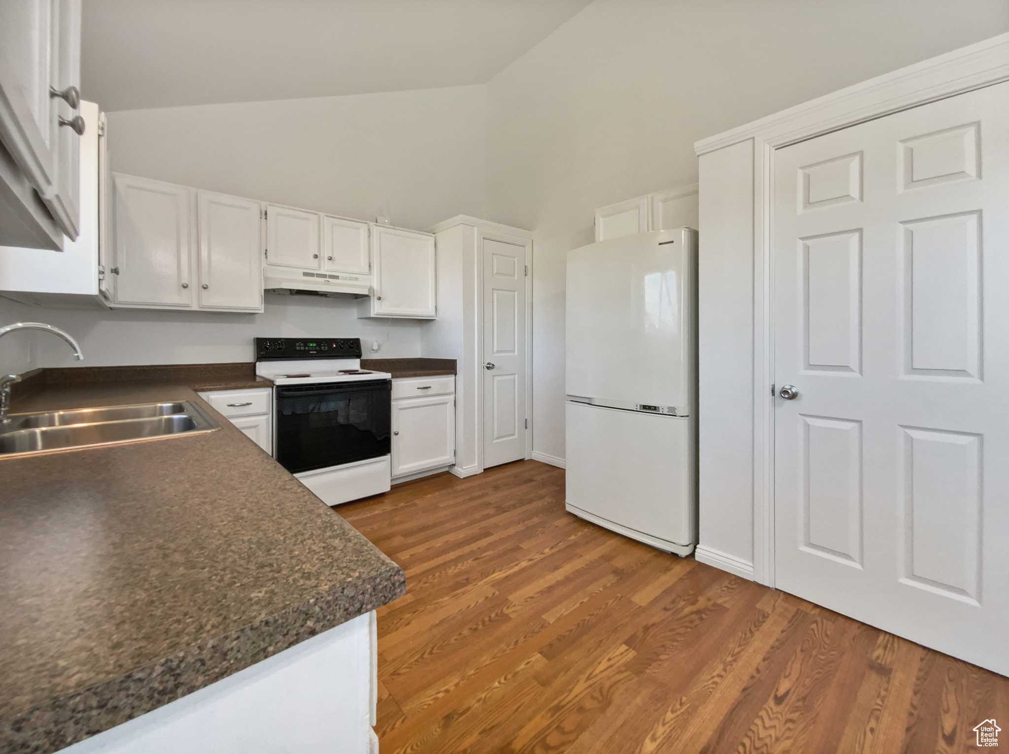 Kitchen with dark countertops, range with electric cooktop, freestanding refrigerator, and a sink