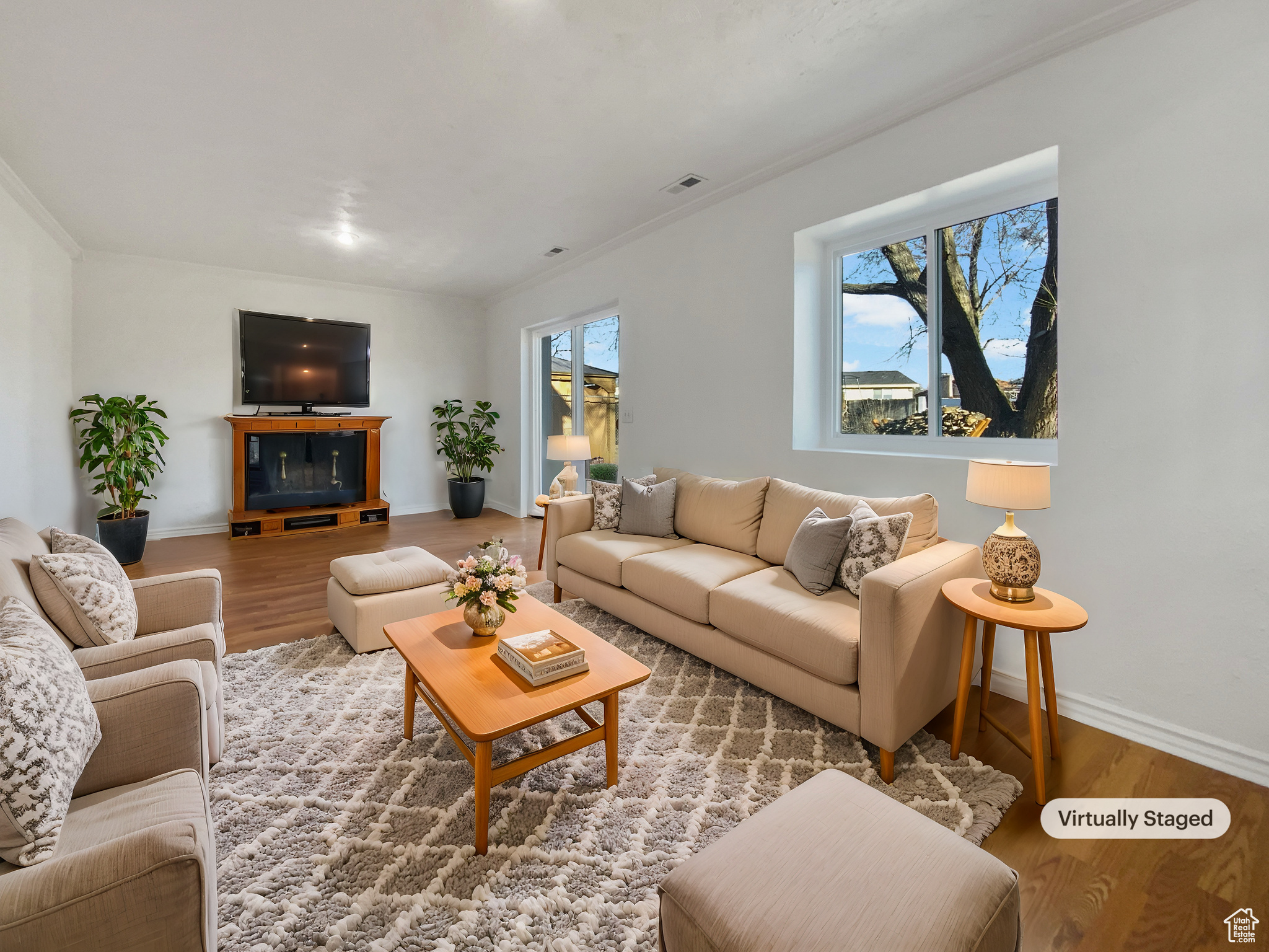 Living room with baseboards, wood finished floors, visible vents, and ornamental molding