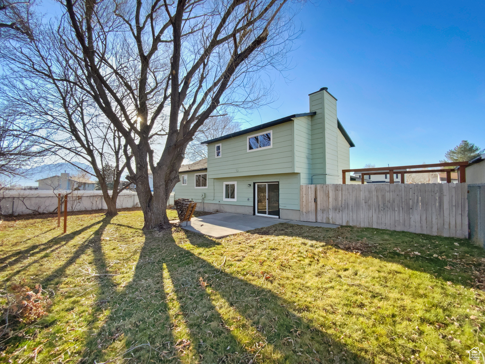 Rear view of house with a patio area, a lawn, a fenced backyard, and a chimney