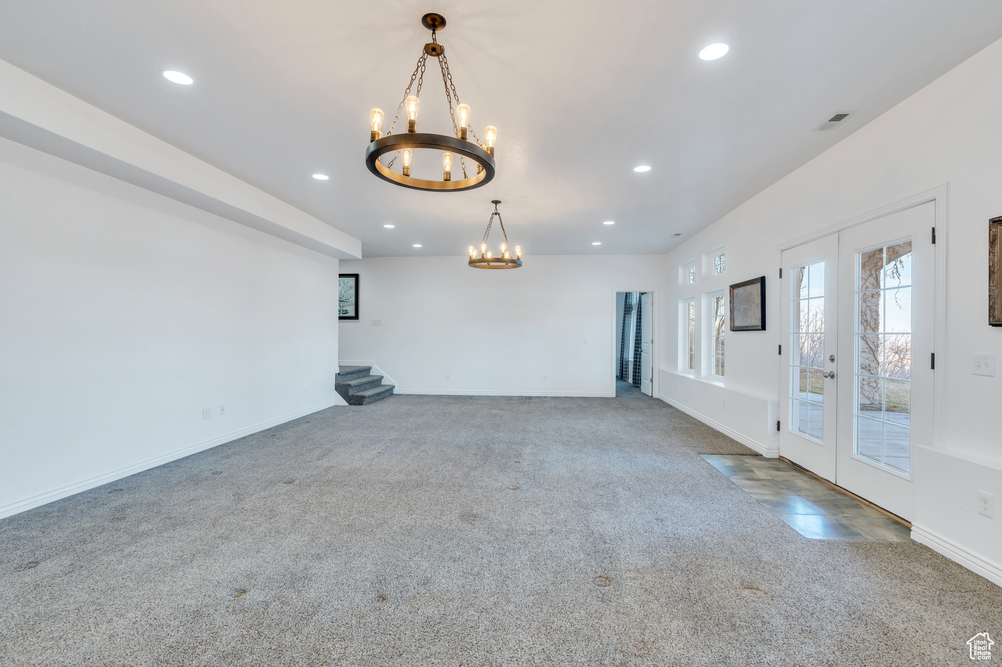 Unfurnished room featuring baseboards, carpet, recessed lighting, french doors, and a notable chandelier