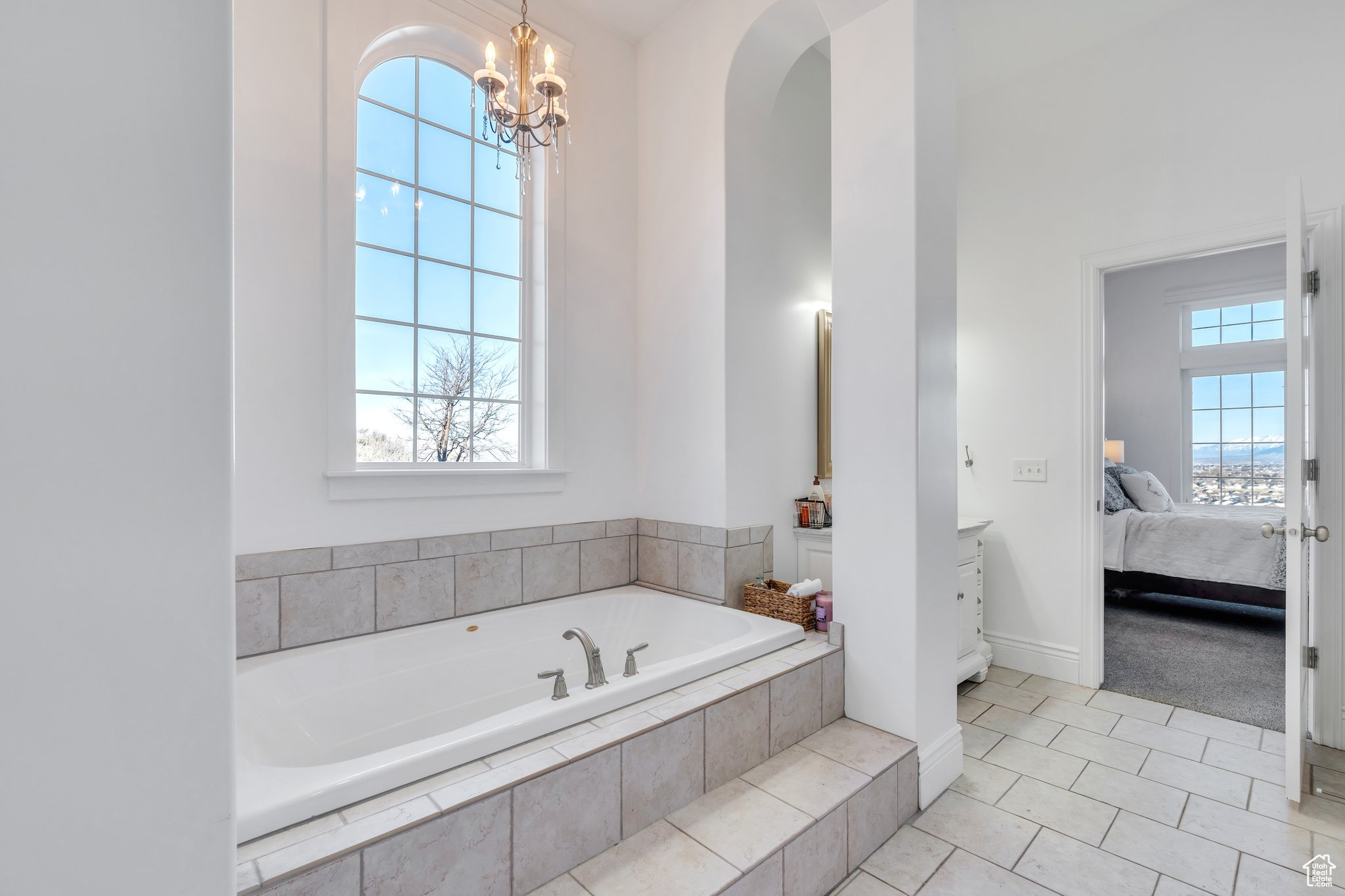 Full bath with tile patterned floors, connected bathroom, an inviting chandelier, and a bath