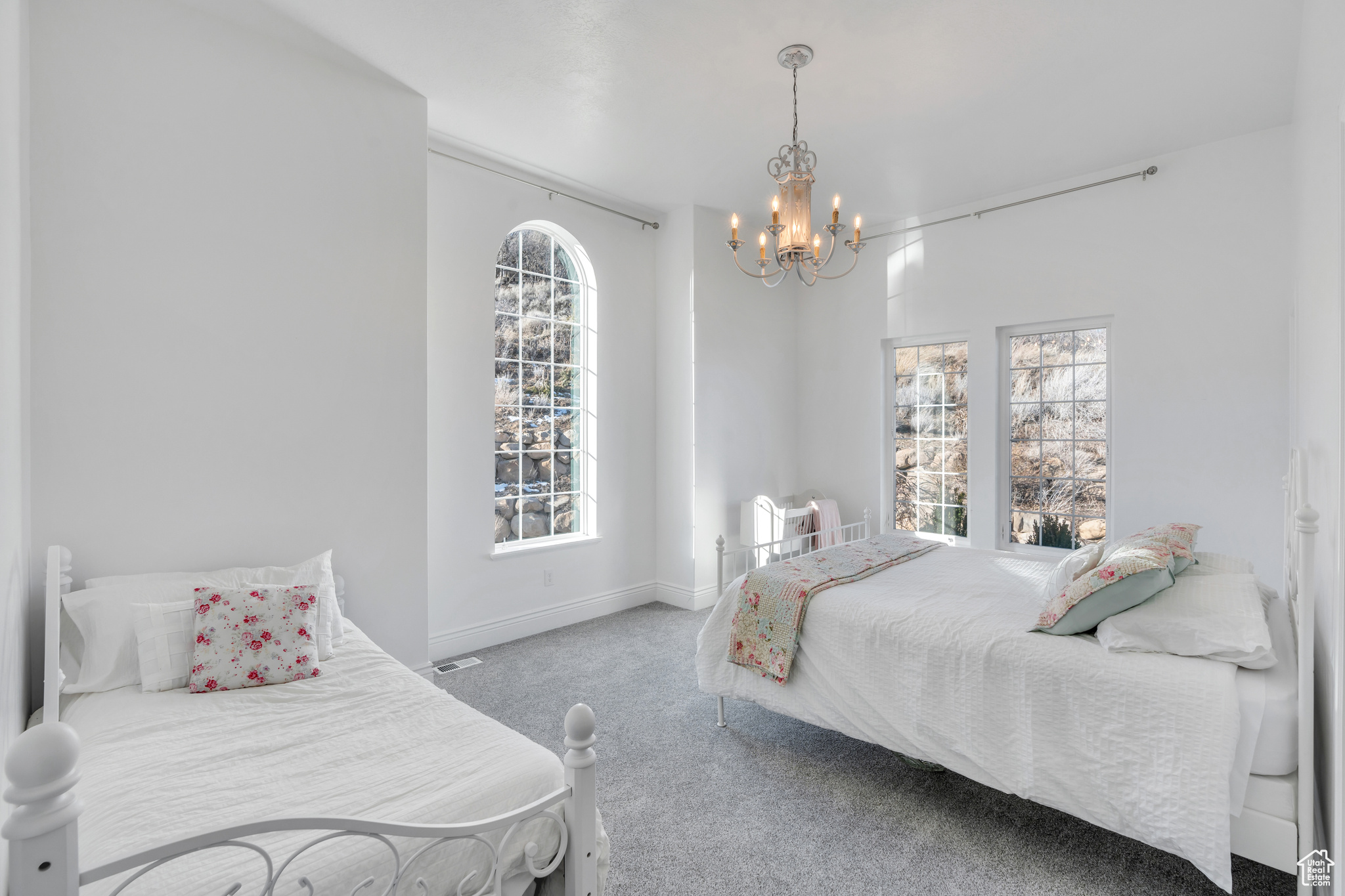 Carpeted bedroom featuring a notable chandelier and baseboards