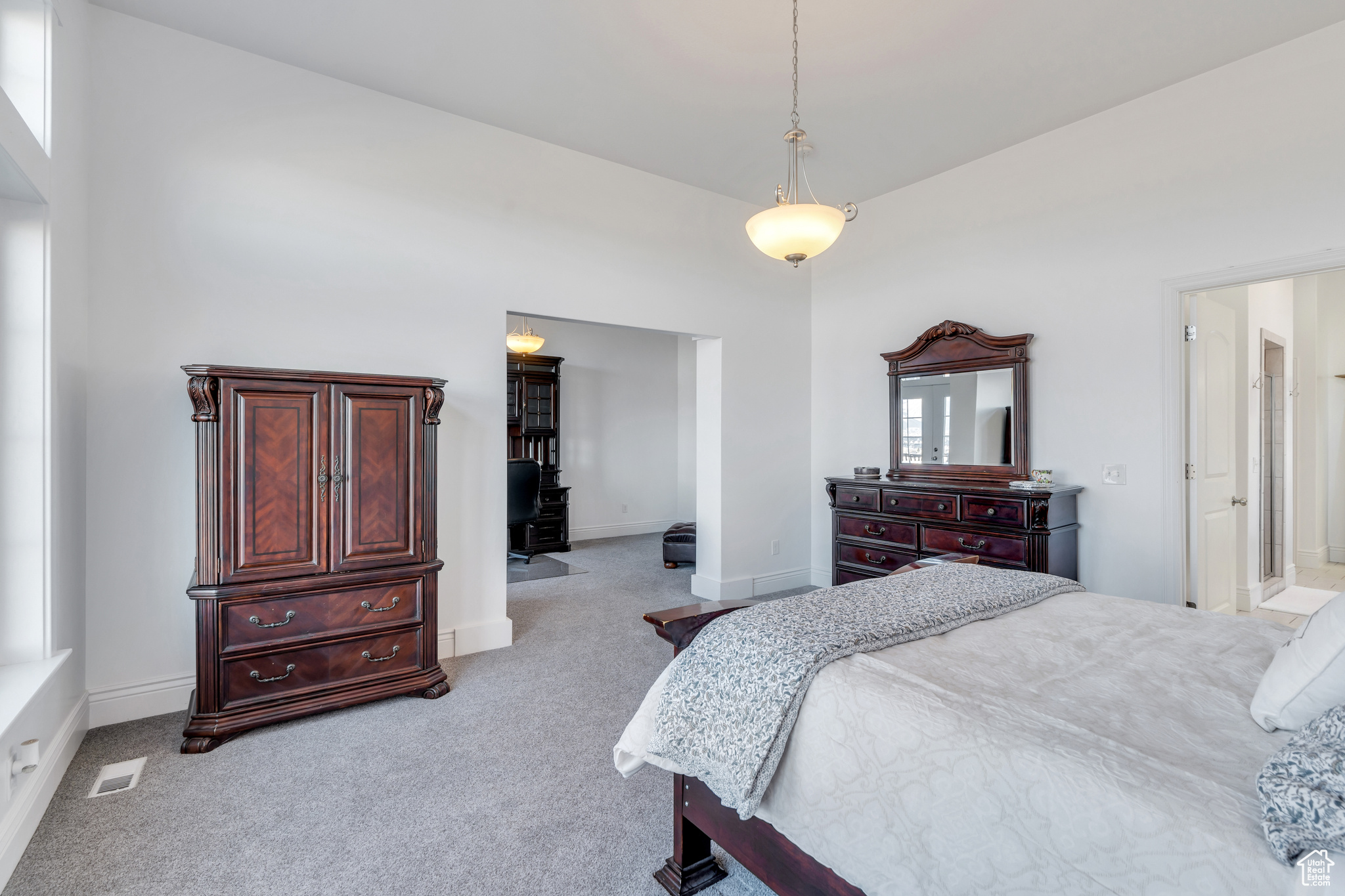 Carpeted bedroom with visible vents, baseboards, and a high ceiling