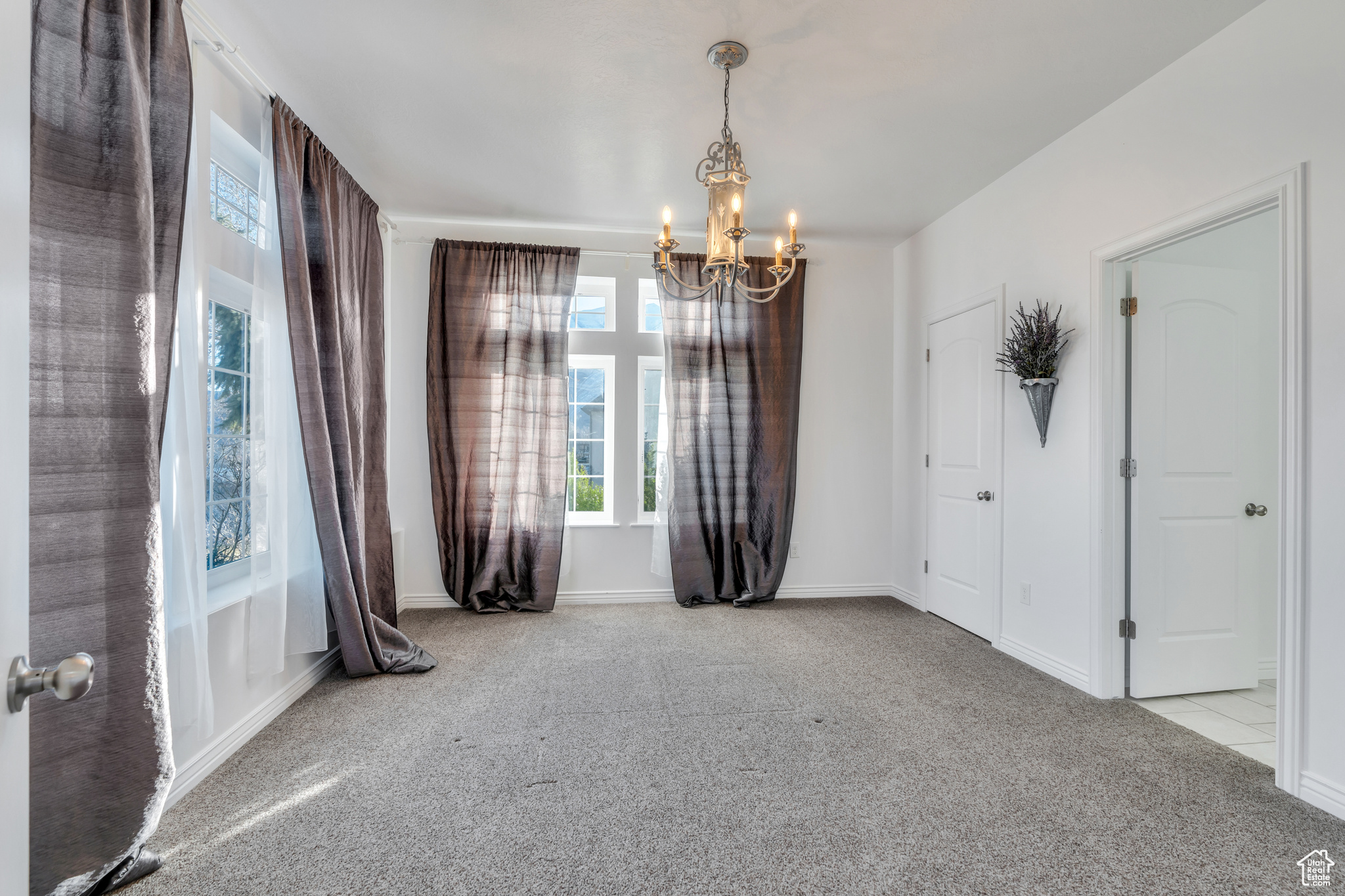 Empty room with an inviting chandelier, baseboards, and carpet