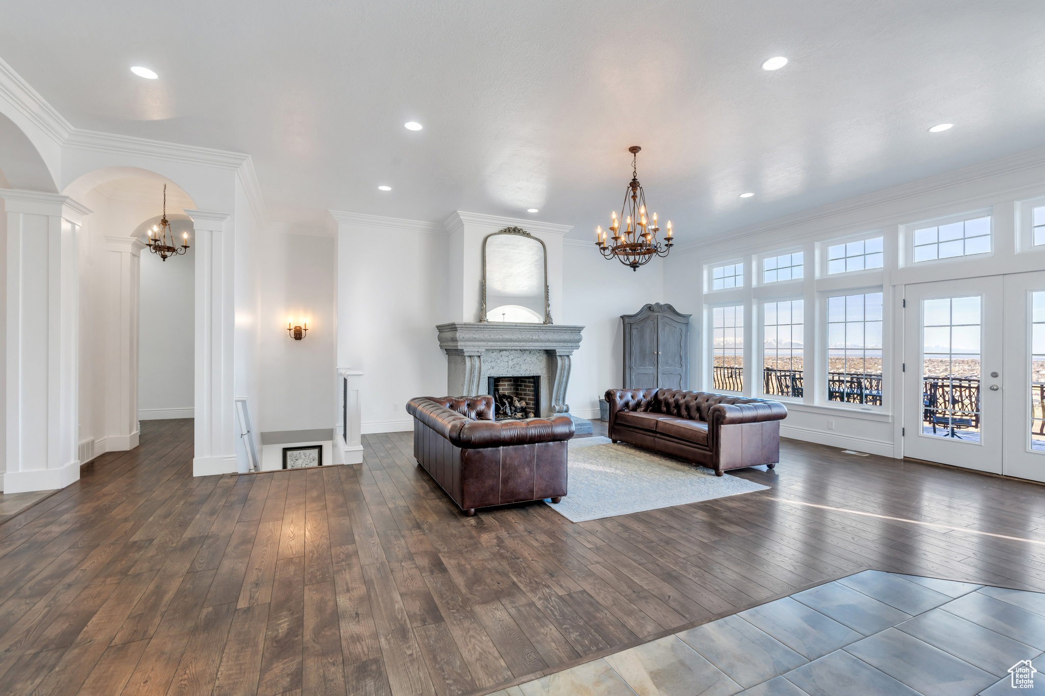 Living room with arched walkways, dark wood finished floors, a fireplace, and an inviting chandelier