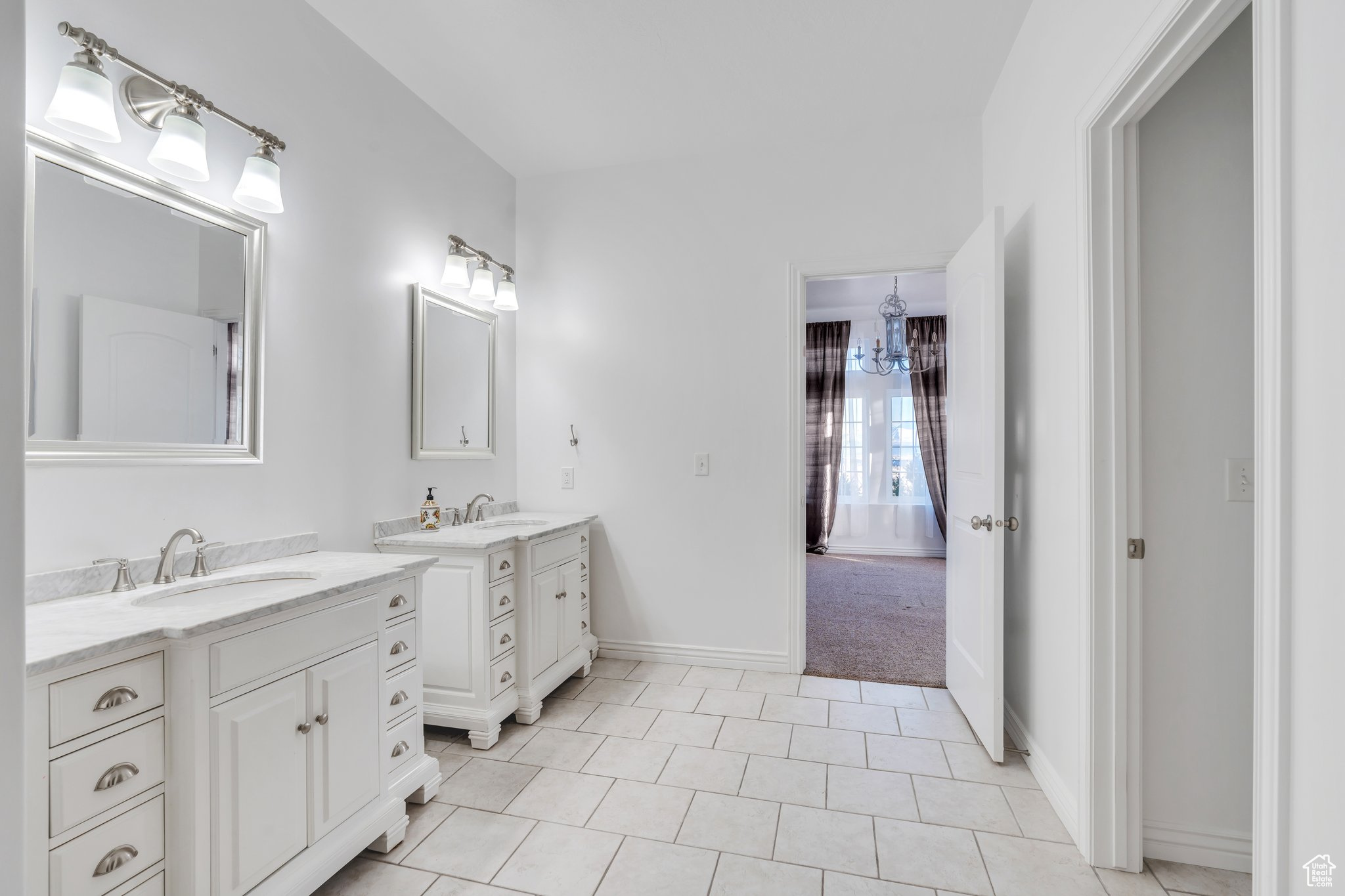 Bathroom featuring a sink, baseboards, two vanities, and tile patterned floors