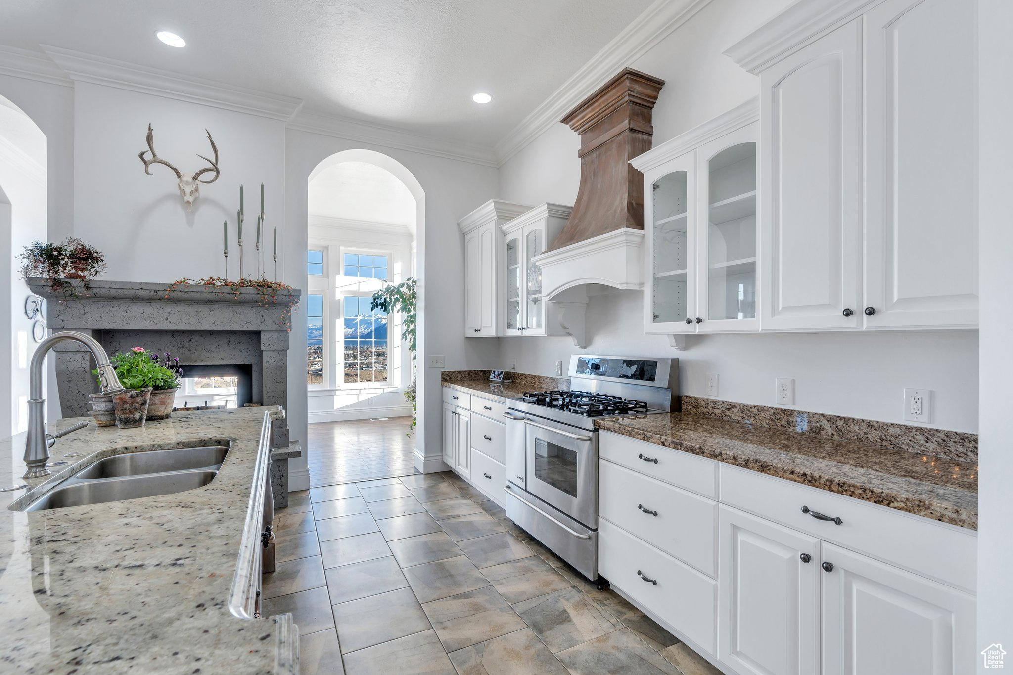 Kitchen featuring a sink, a multi sided fireplace, stainless steel gas stove, and ornamental molding