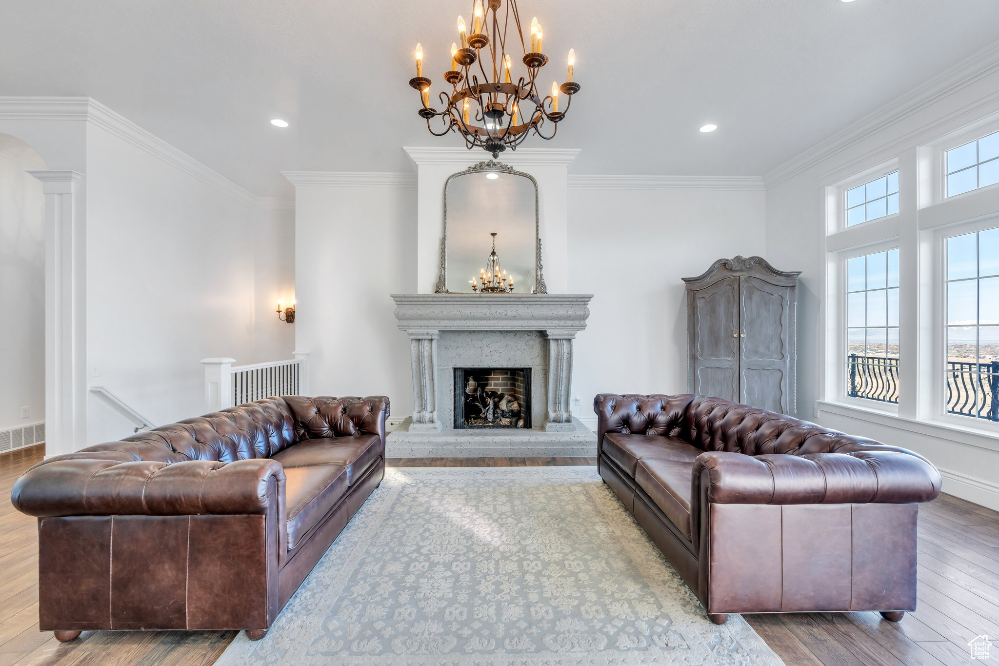 Living area featuring decorative columns, a fireplace with raised hearth, wood finished floors, and ornamental molding