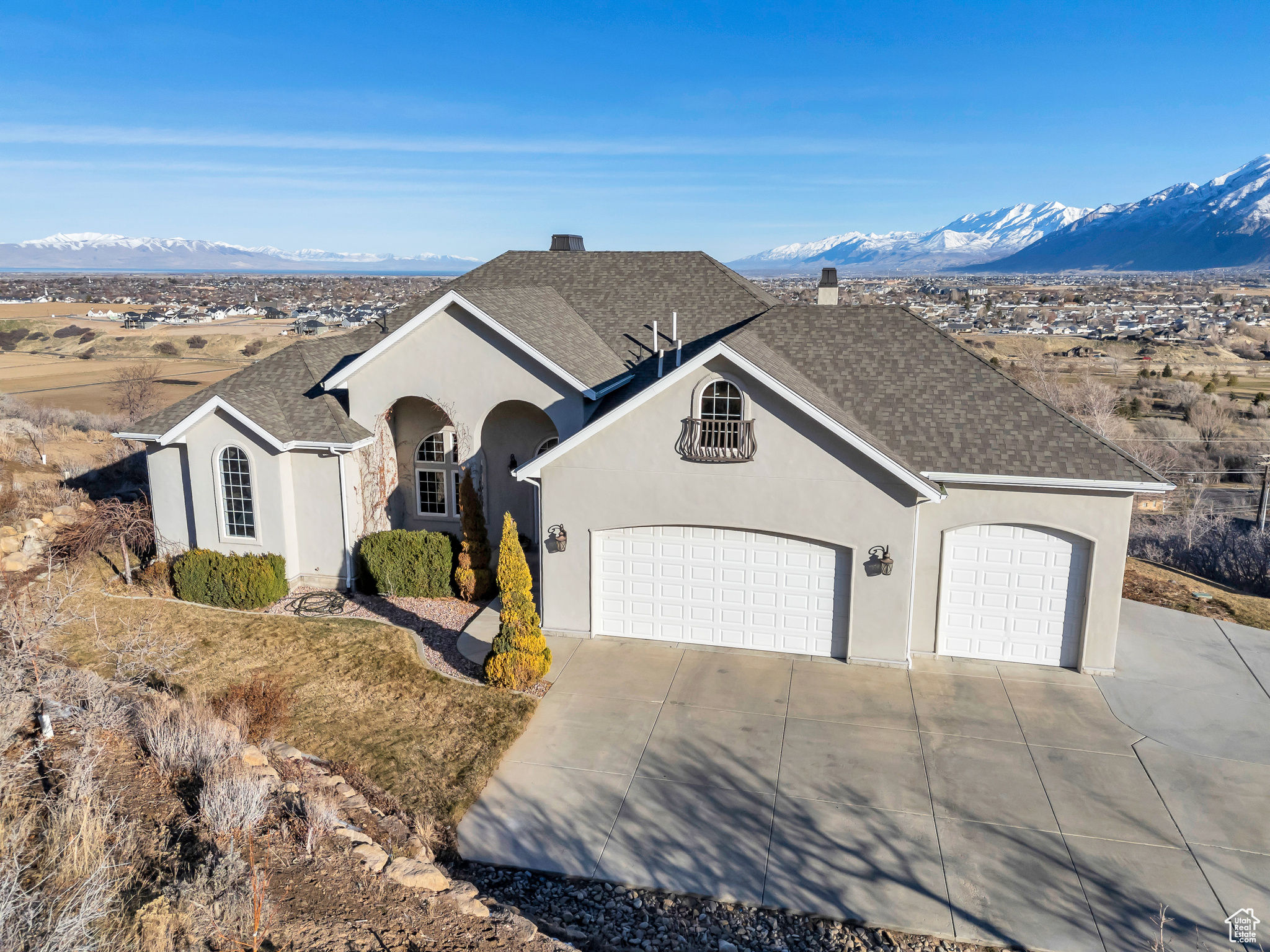 View of front of house with stucco siding, a mountain view, an attached garage, and driveway