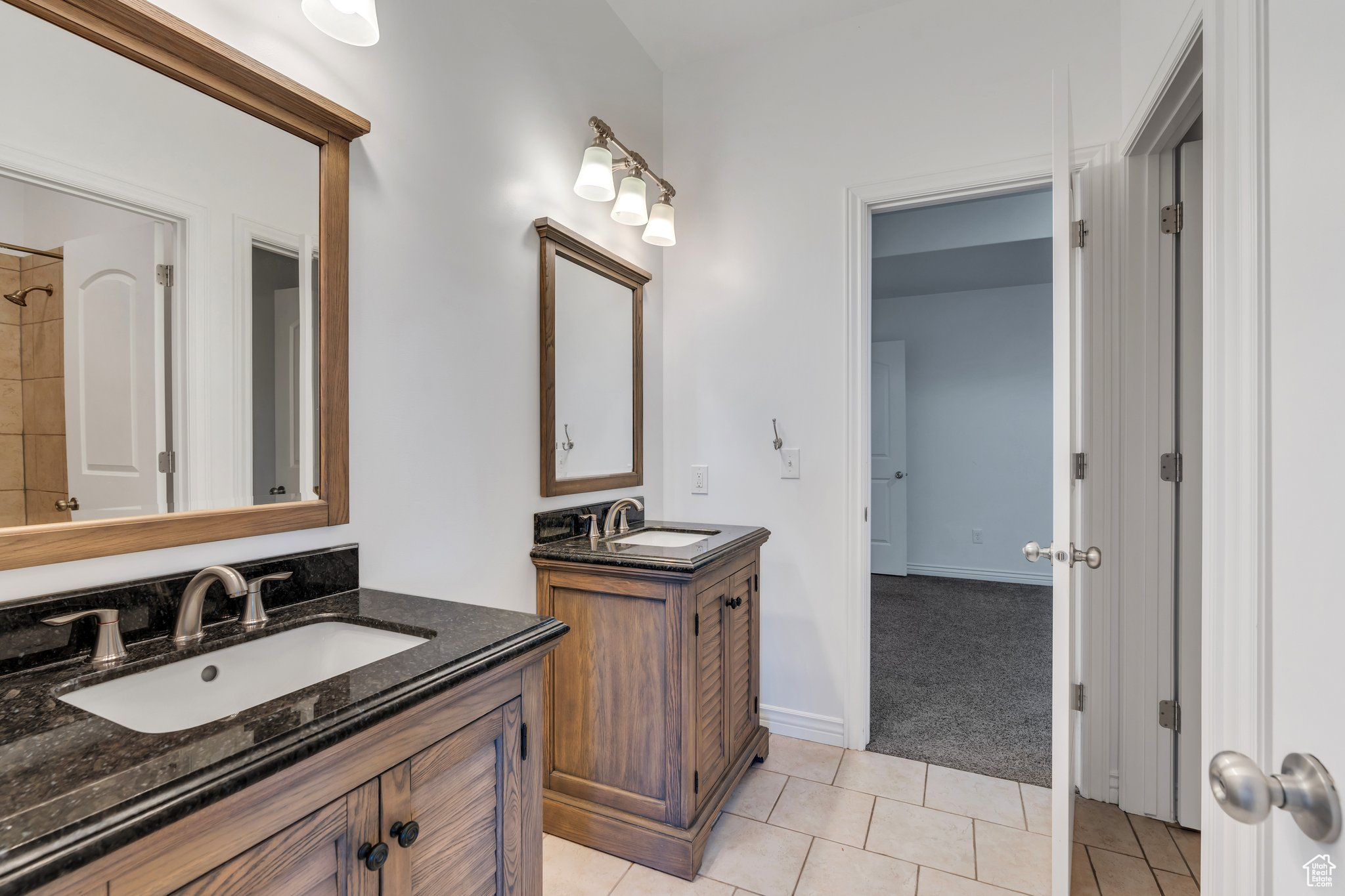 Full bath with tile patterned floors, two vanities, baseboards, and a sink