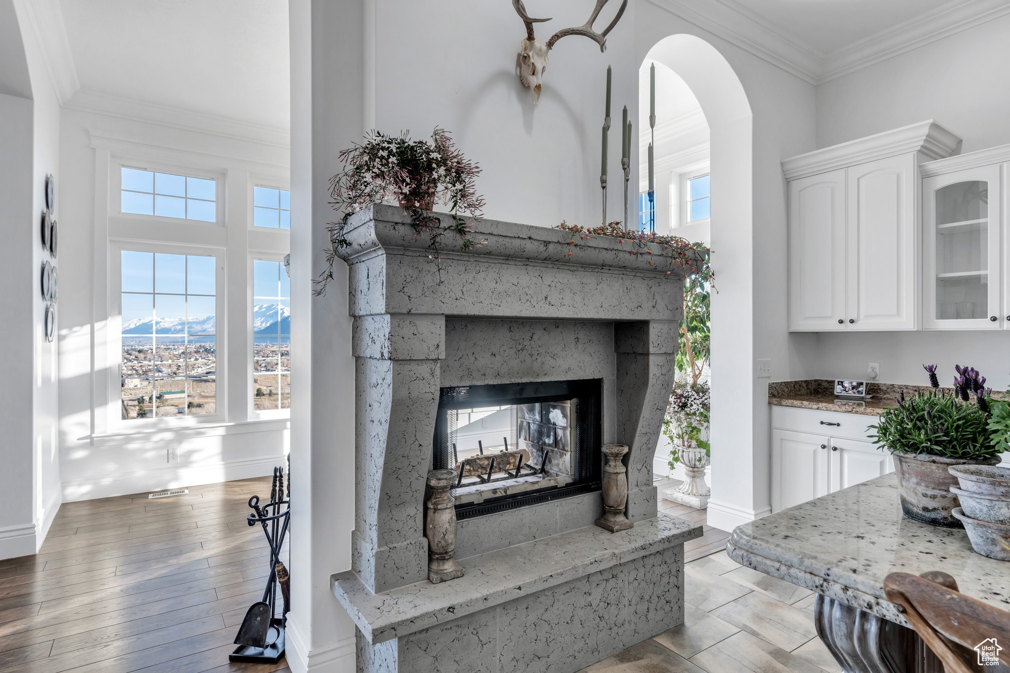 Details featuring a multi sided fireplace, arched walkways, wood finished floors, and crown molding