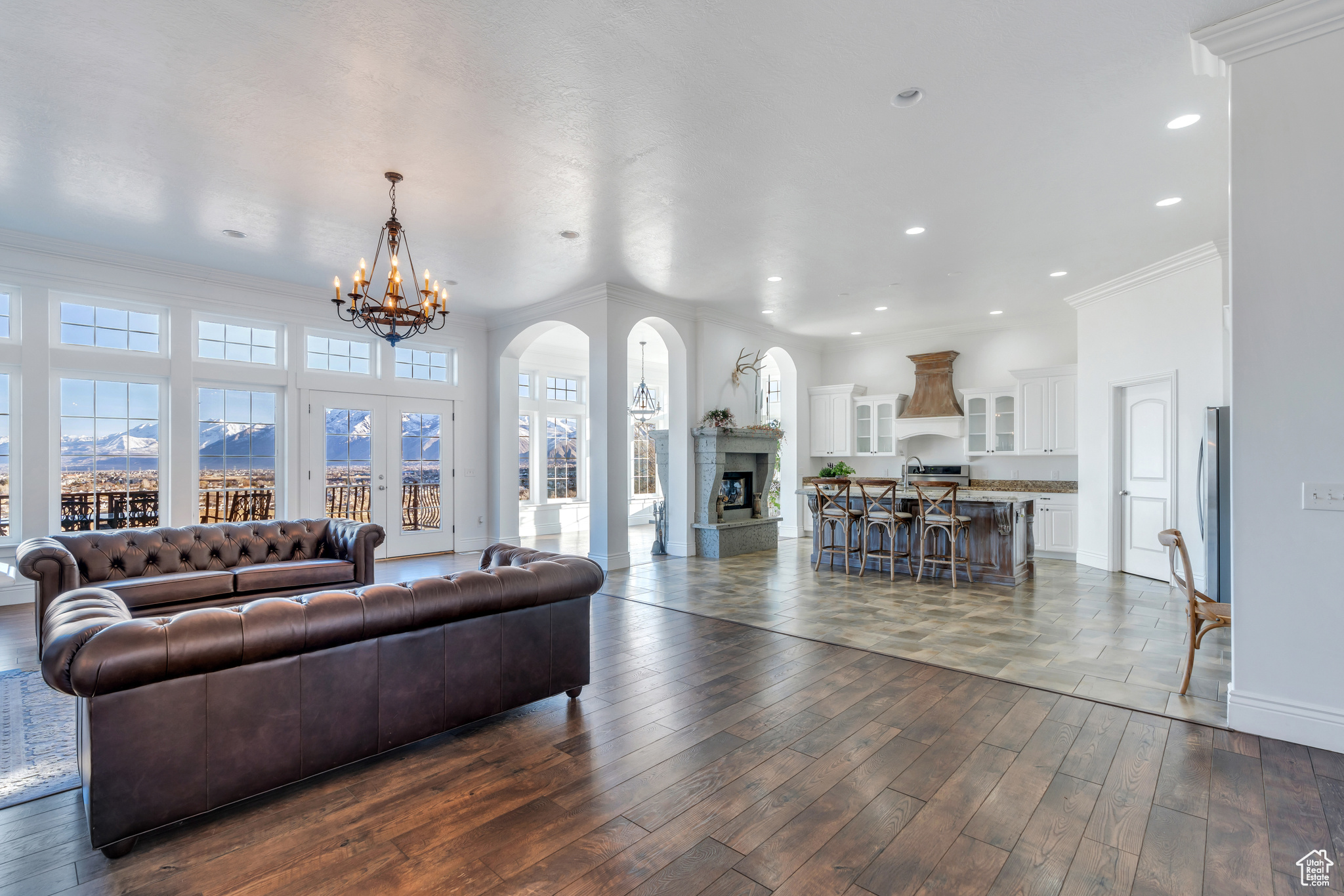 Living room featuring baseboards, a fireplace with raised hearth, dark wood-type flooring, crown molding, and a notable chandelier