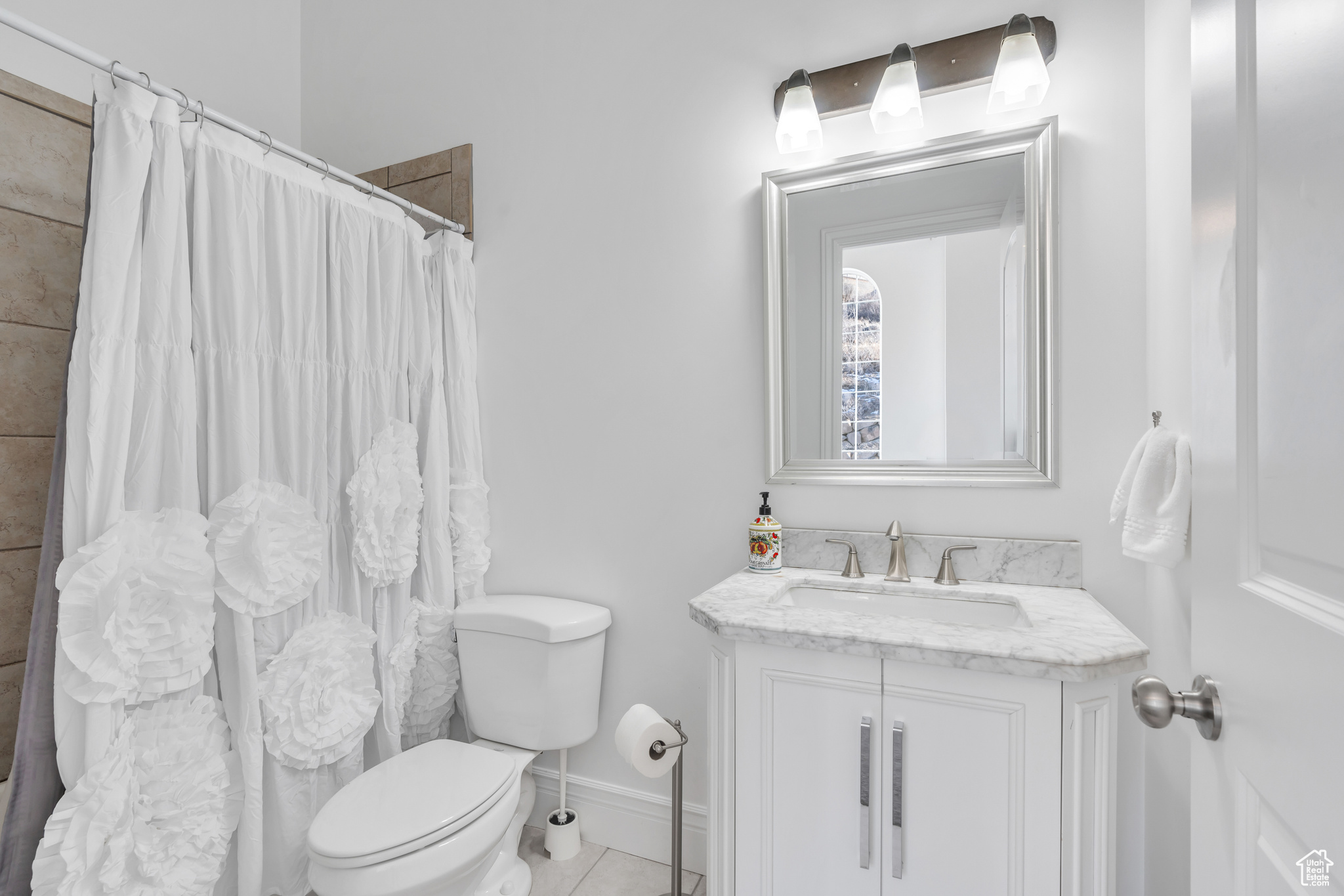 Full bath with tile patterned floors, toilet, a shower with shower curtain, baseboards, and vanity