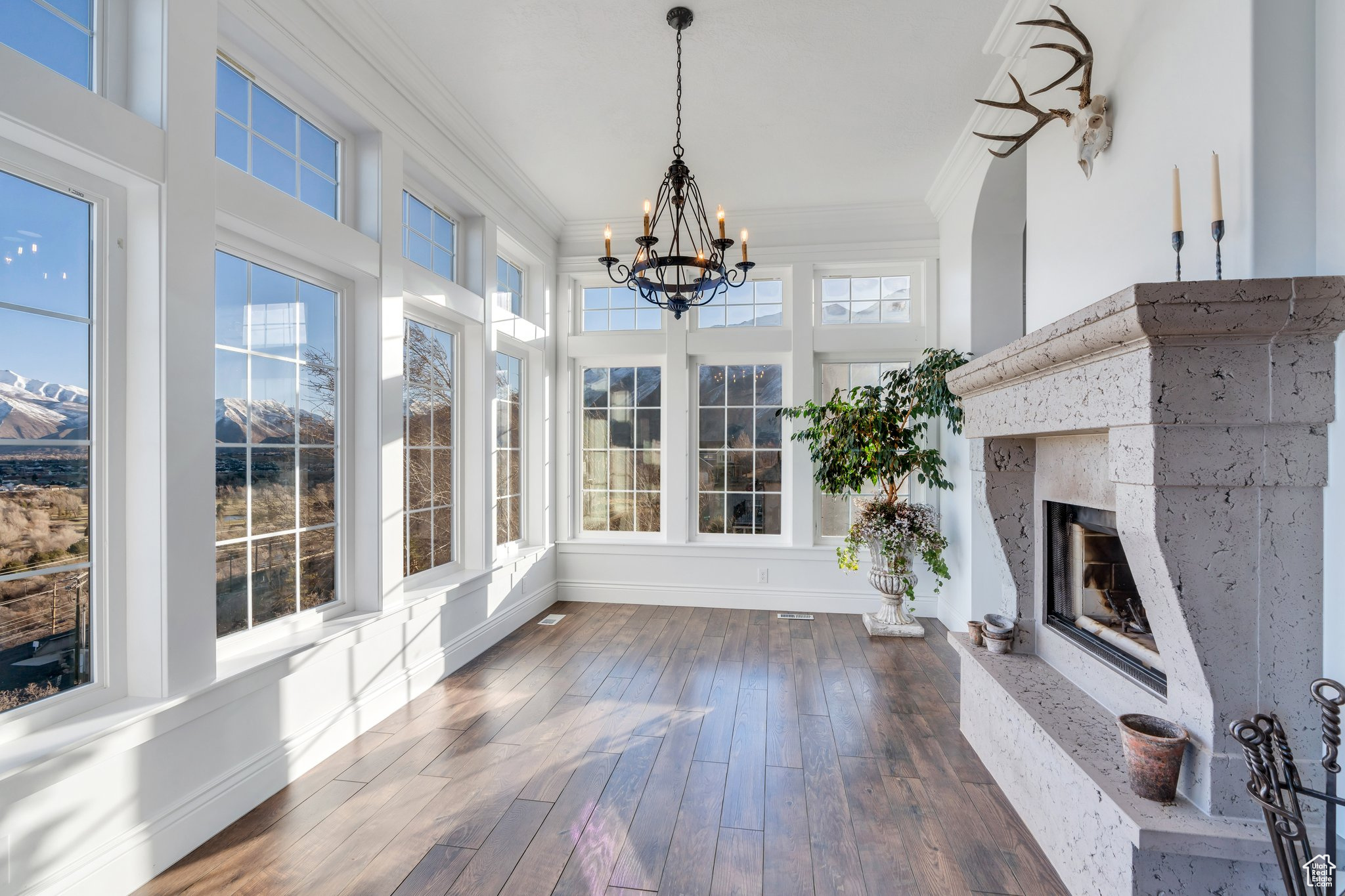 Unfurnished sunroom featuring a healthy amount of sunlight, a high end fireplace, and an inviting chandelier