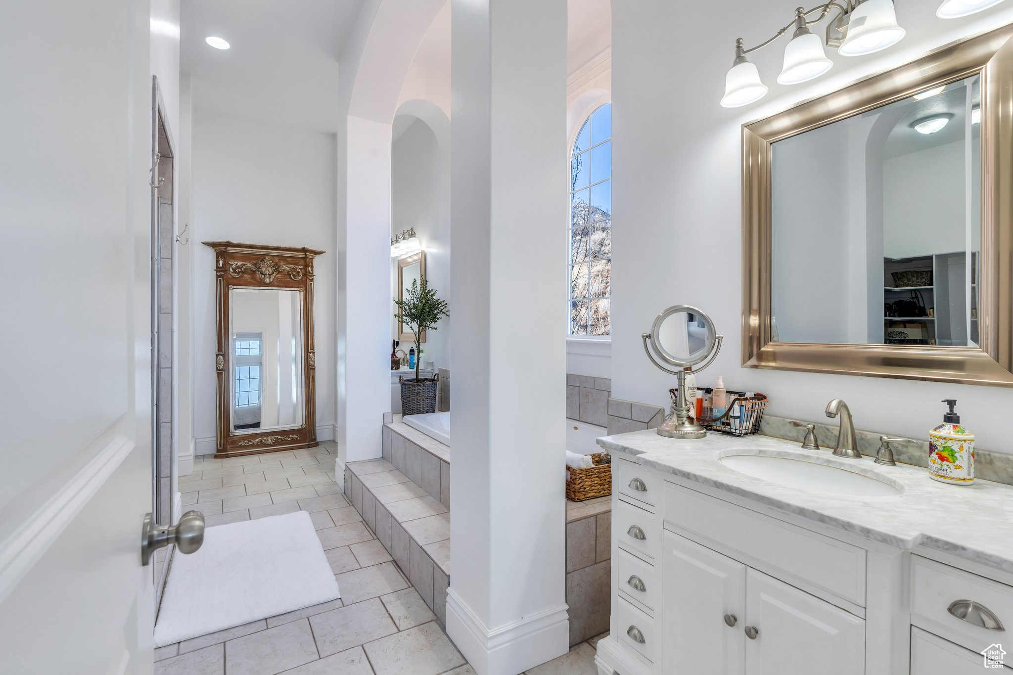 Bathroom with tile patterned floors, a healthy amount of sunlight, a bath, and vanity