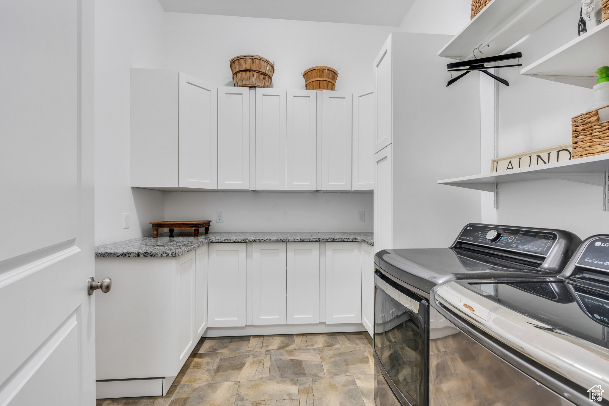 Laundry room with cabinet space, independent washer and dryer, and stone finish floor