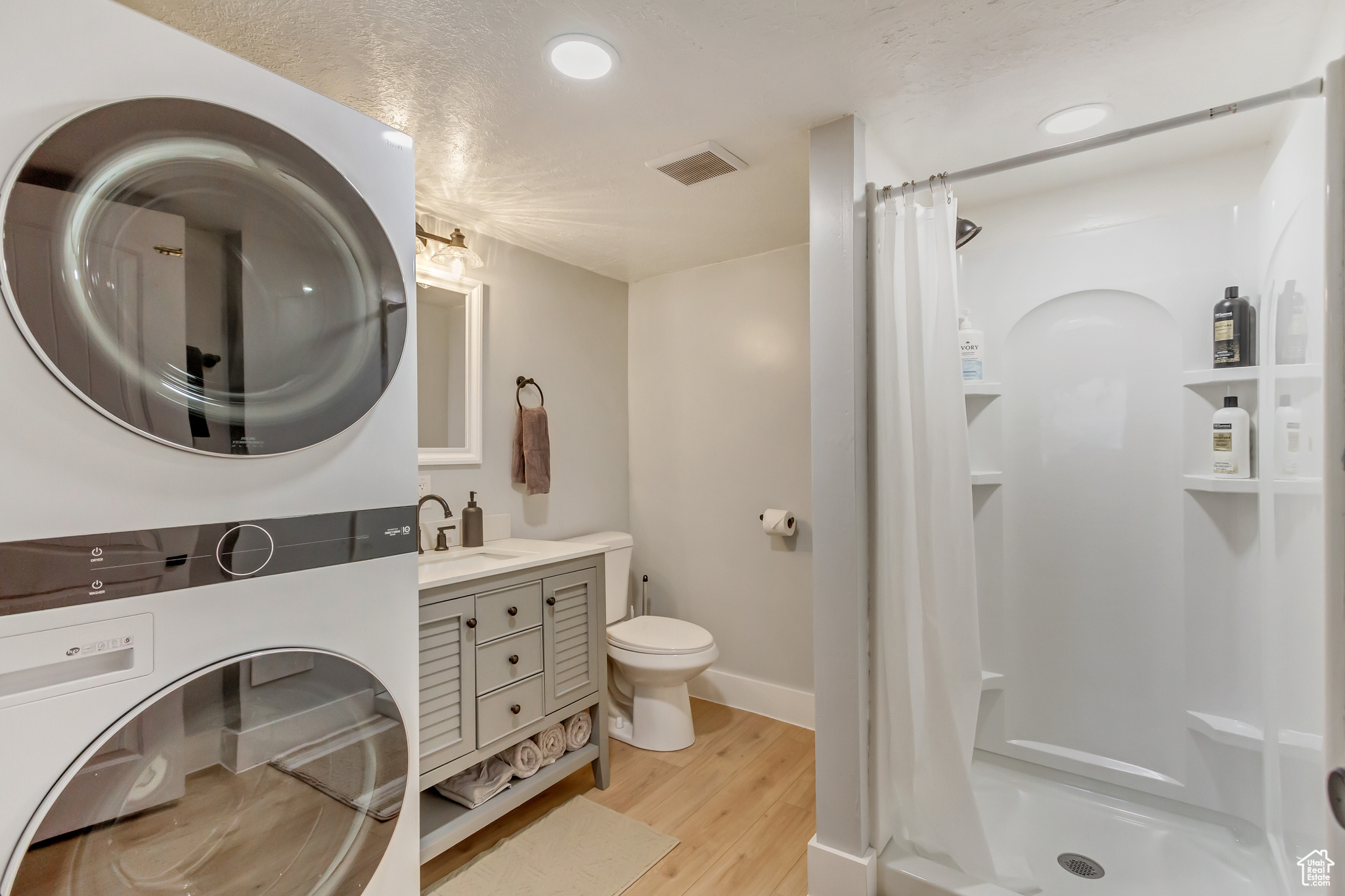 Bathroom featuring visible vents, a shower stall, toilet, wood finished floors, and vanity