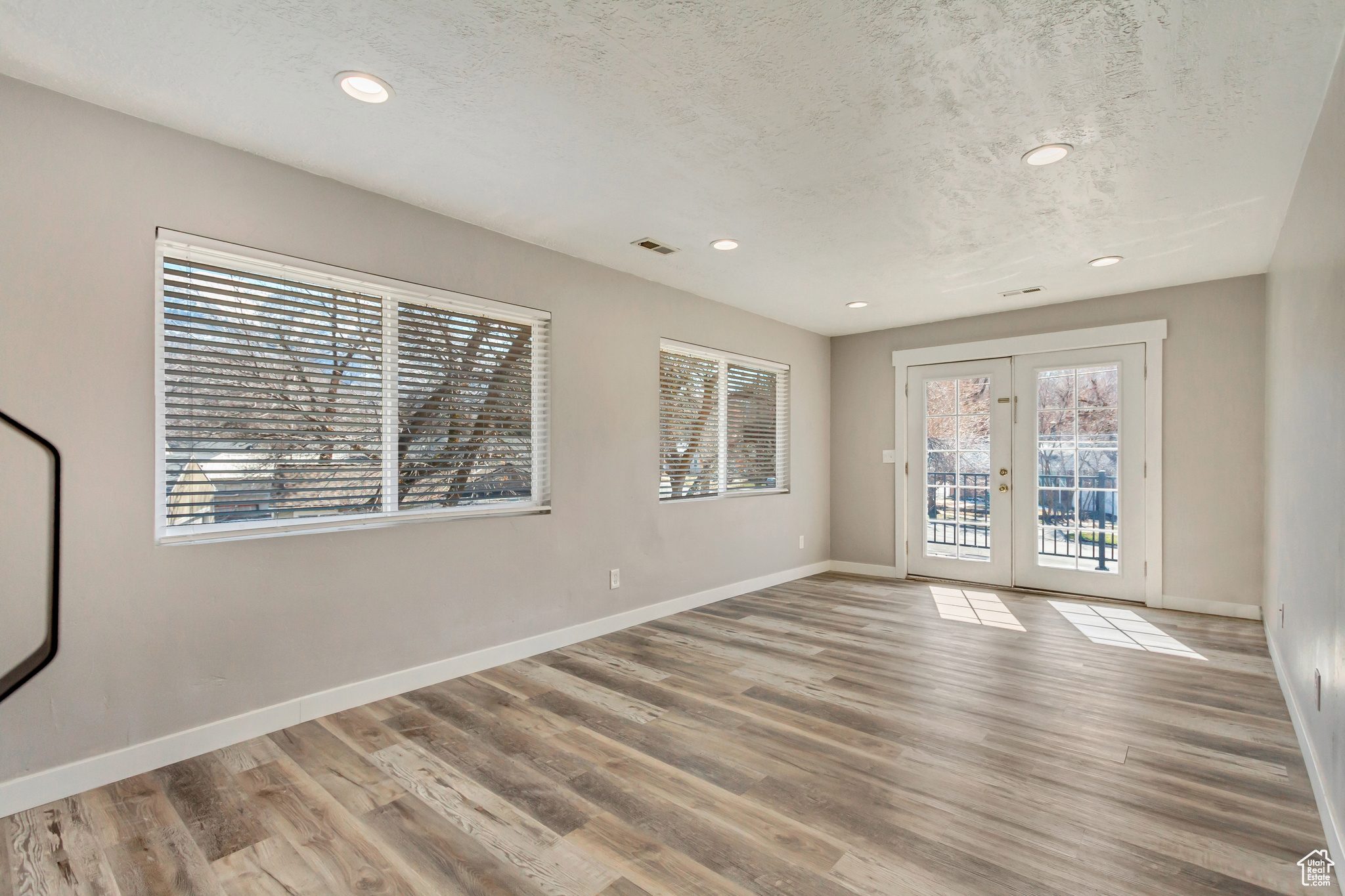 Empty room with visible vents, baseboards, a textured ceiling, and wood finished floors