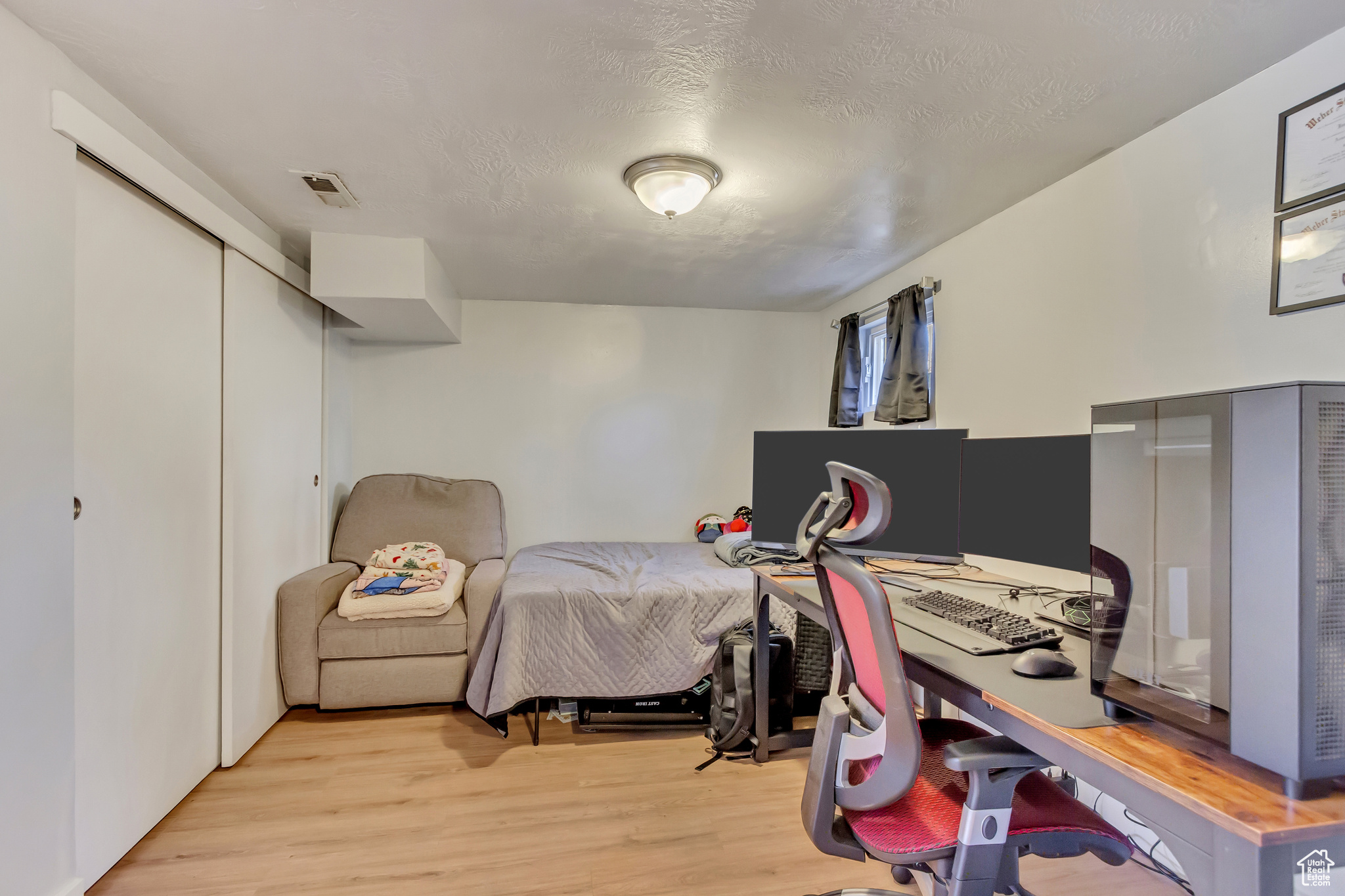 Bedroom featuring a closet, visible vents, a textured ceiling, and light wood-type flooring