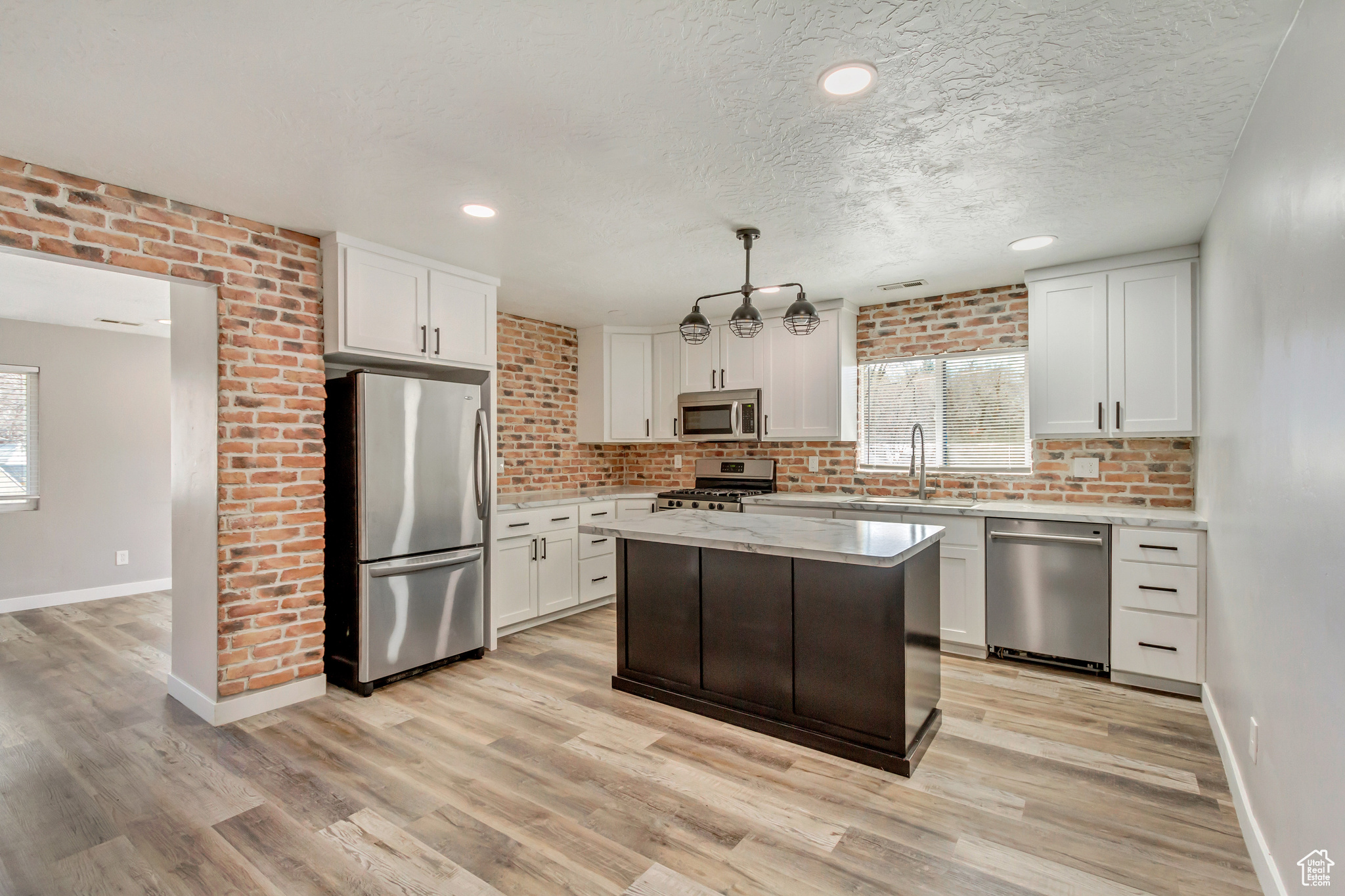 Kitchen with light wood finished floors, plenty of natural light, stainless steel appliances, and a sink