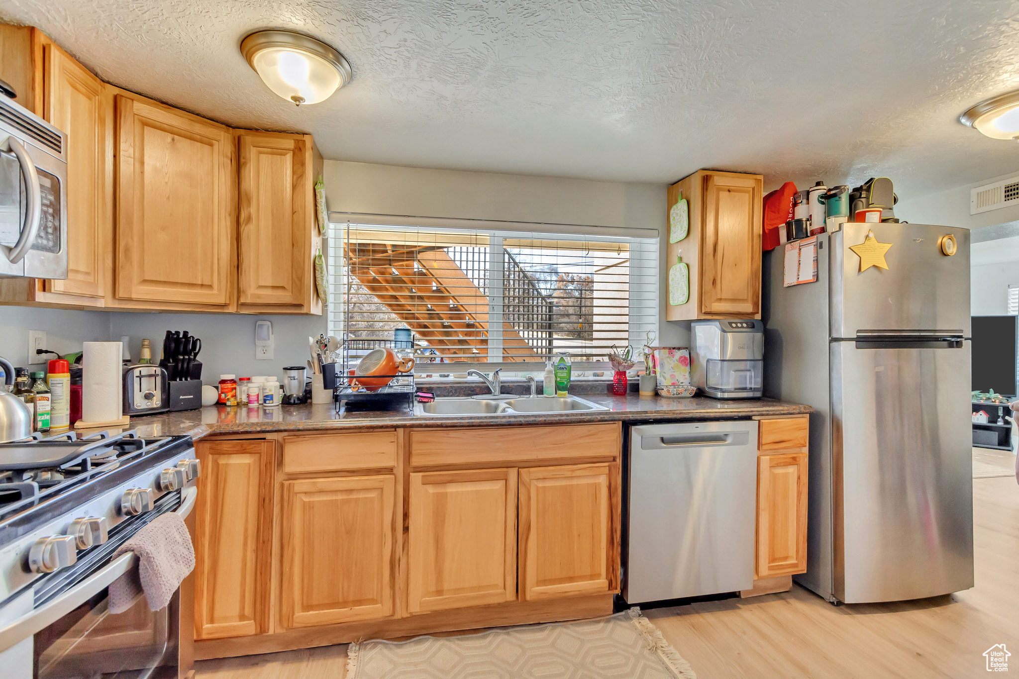 Kitchen with visible vents, light wood finished floors, a sink, appliances with stainless steel finishes, and a textured ceiling