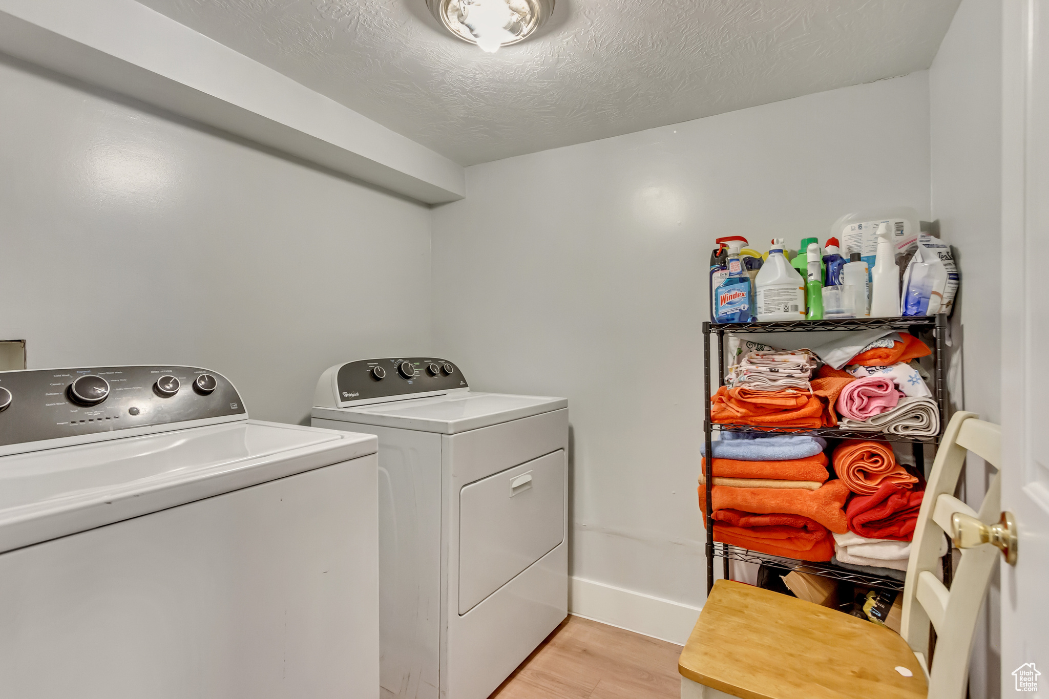 Washroom with baseboards, light wood-type flooring, laundry area, a textured ceiling, and independent washer and dryer