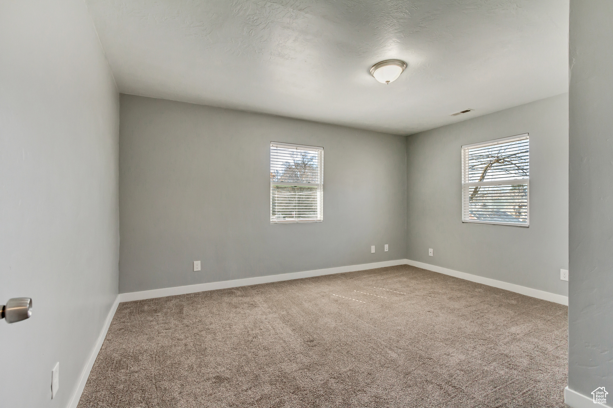 Carpeted spare room featuring baseboards, plenty of natural light, and visible vents