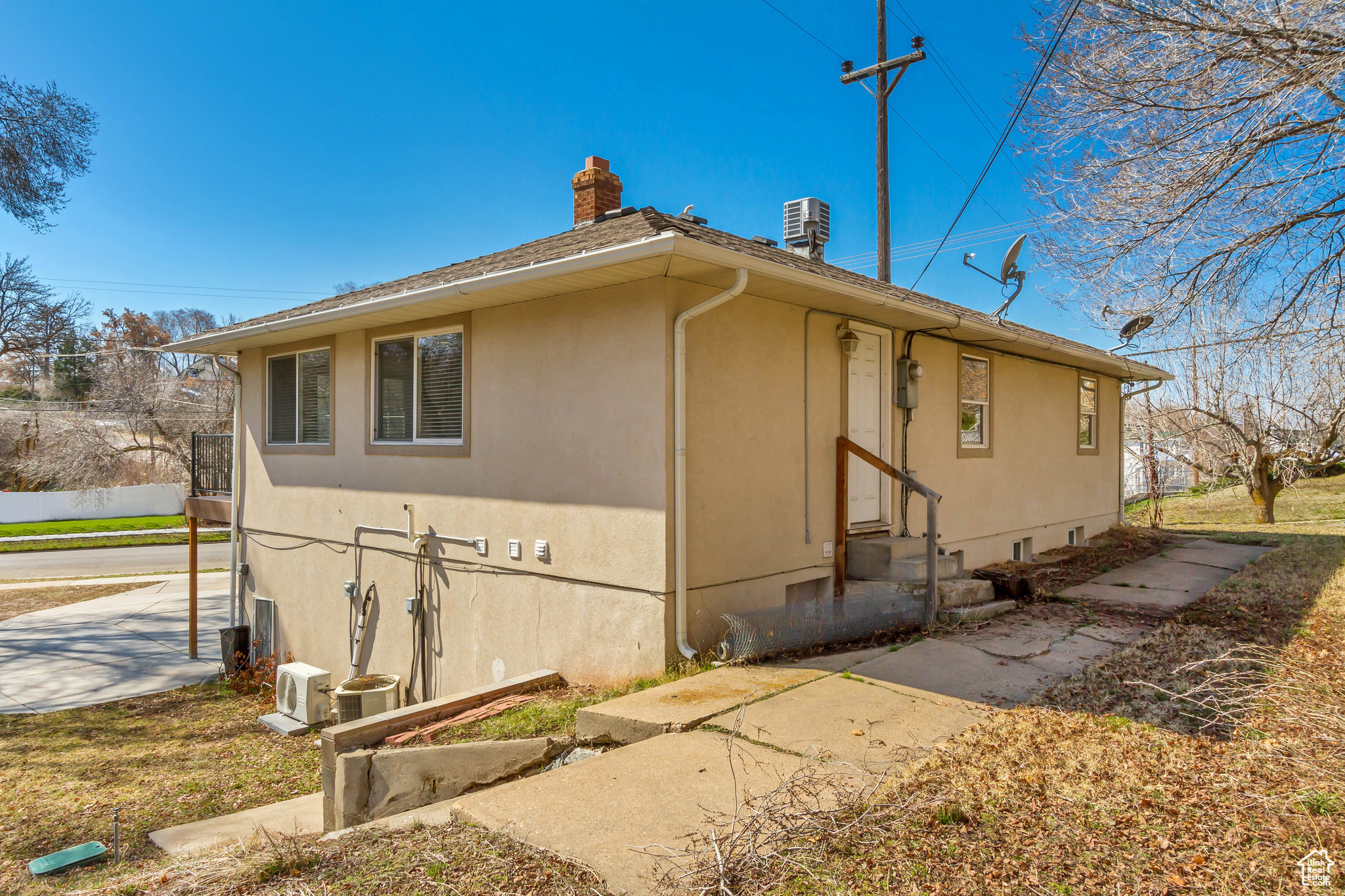 View of side of home featuring central AC unit, stucco siding, entry steps, and a chimney