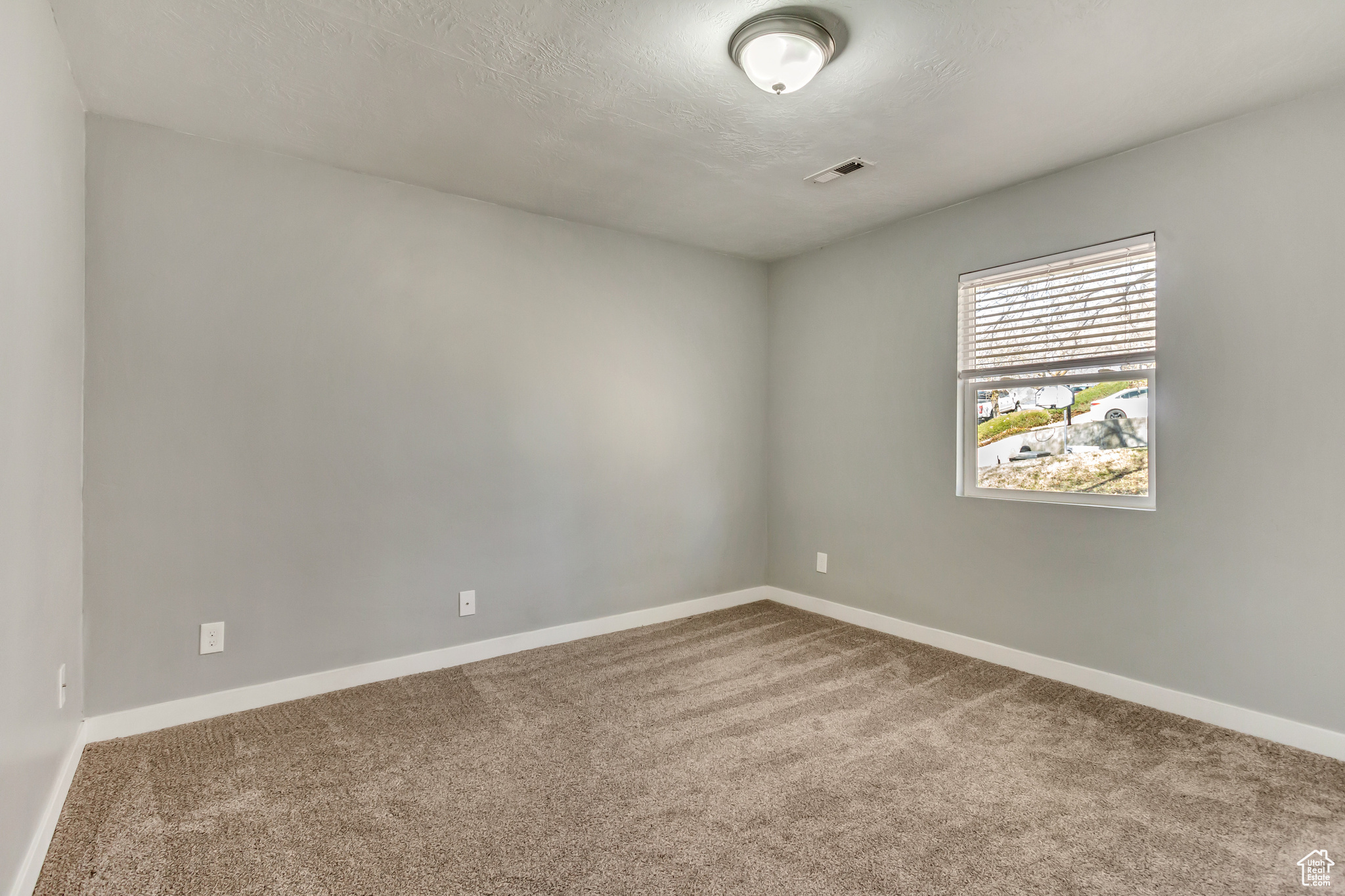 Unfurnished room featuring baseboards, visible vents, carpet floors, and a textured ceiling