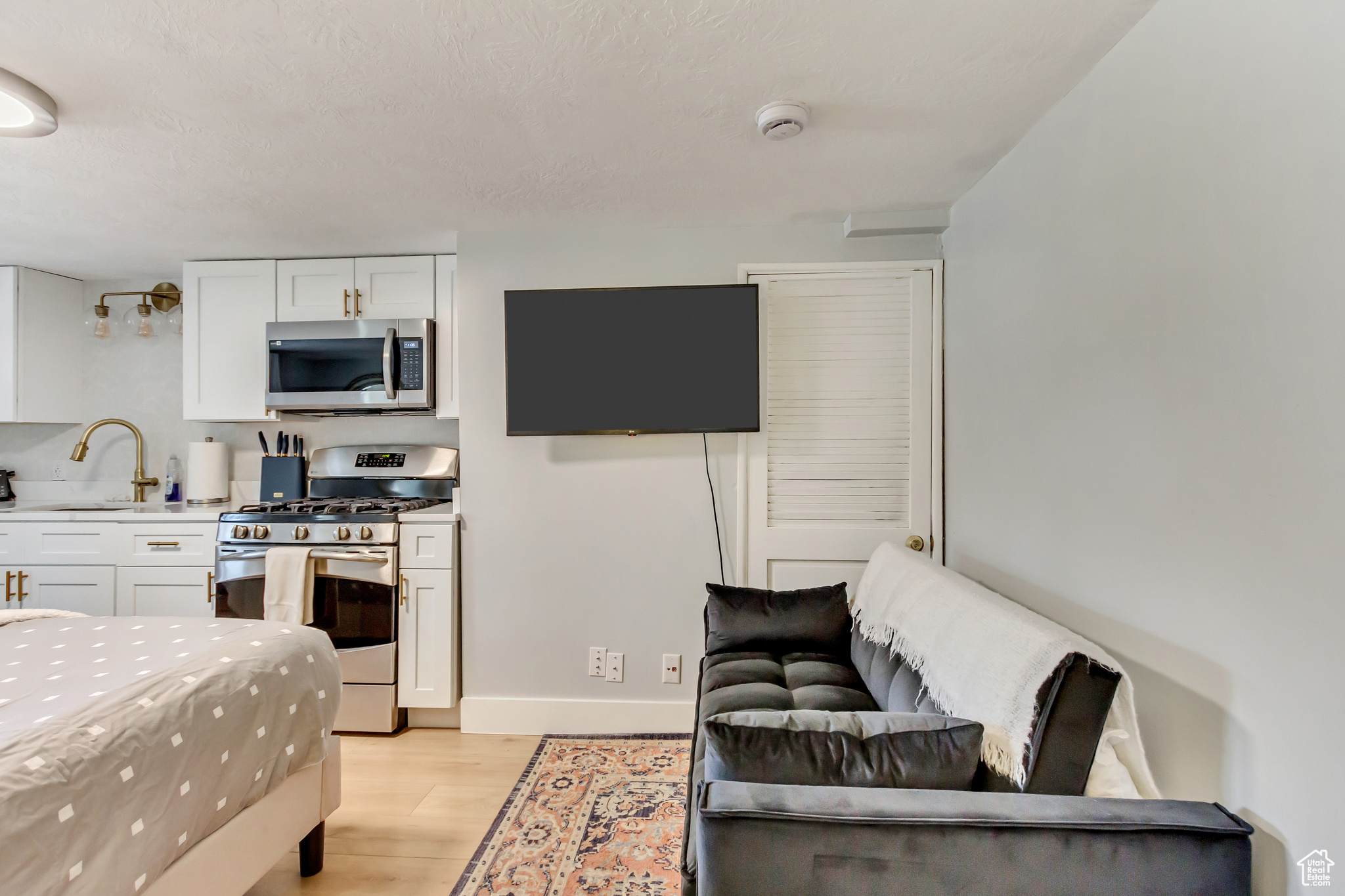 Interior space featuring a sink, light wood-type flooring, appliances with stainless steel finishes, and white cabinetry