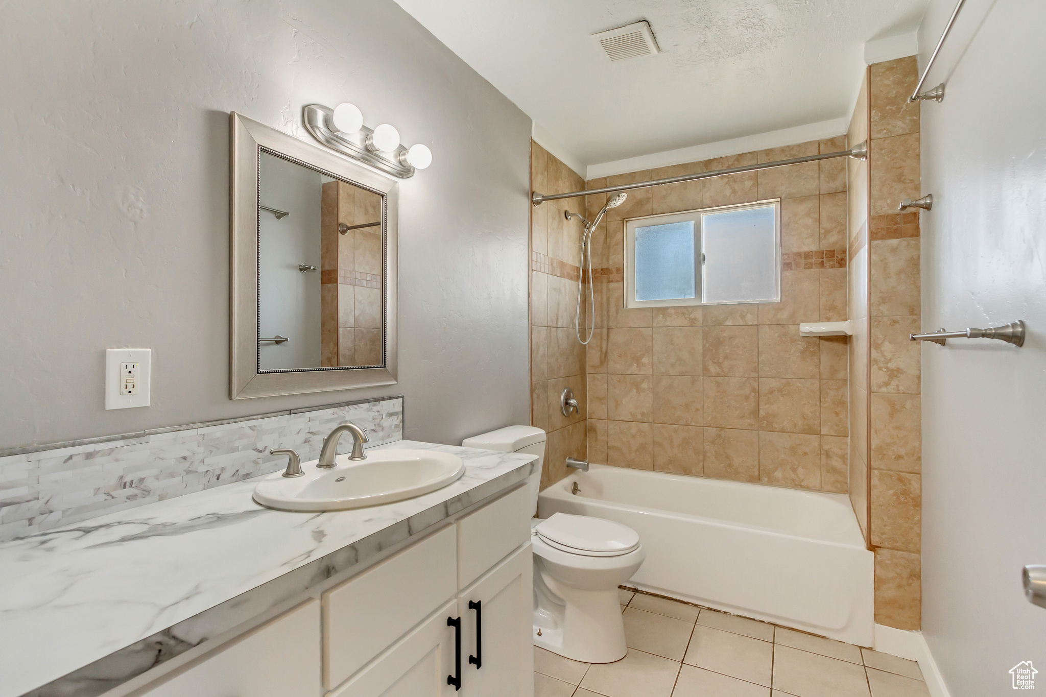 Full bath with visible vents, washtub / shower combination, toilet, tile patterned floors, and vanity