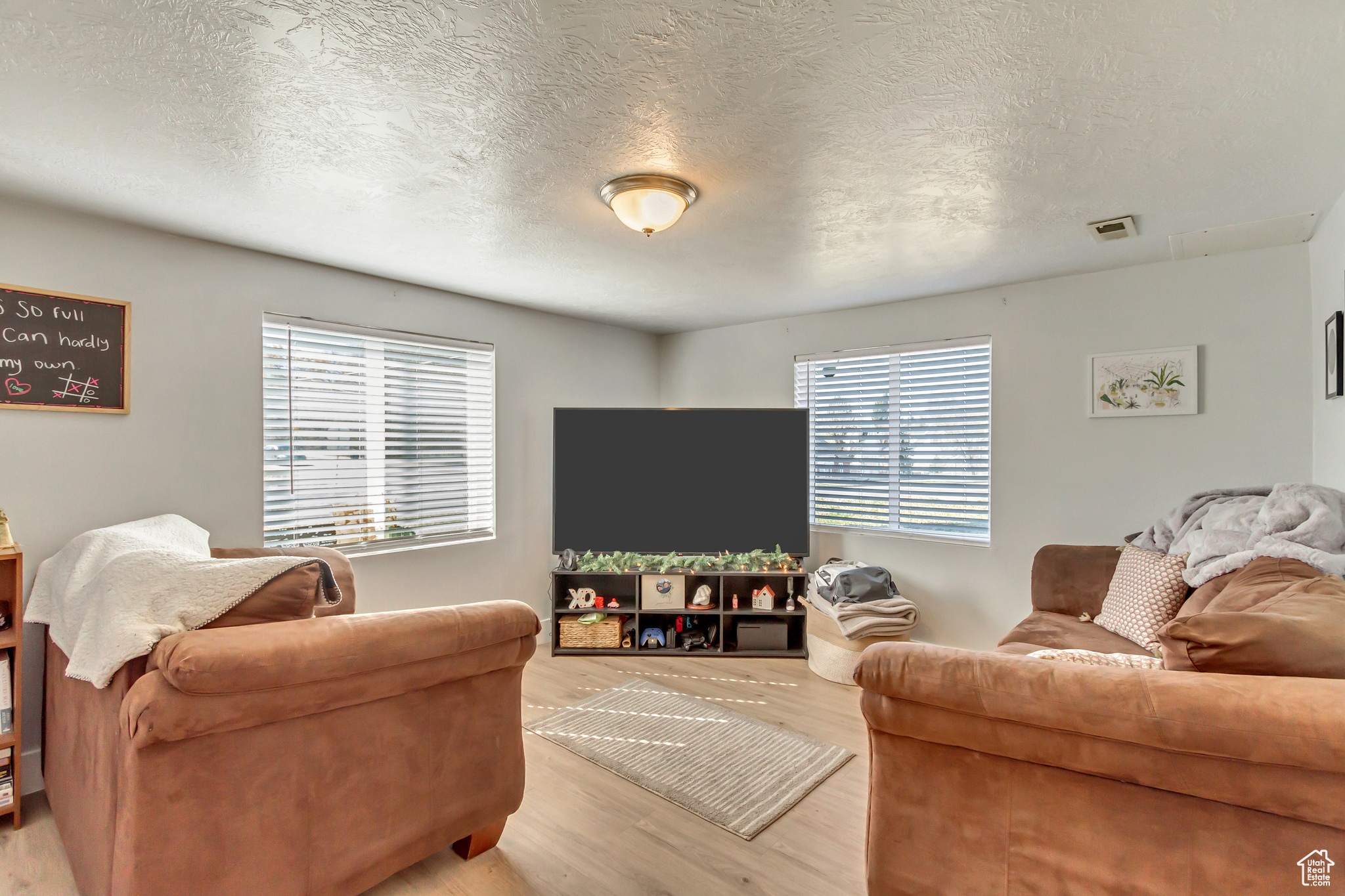 Living area featuring visible vents, a textured ceiling, and light wood-type flooring