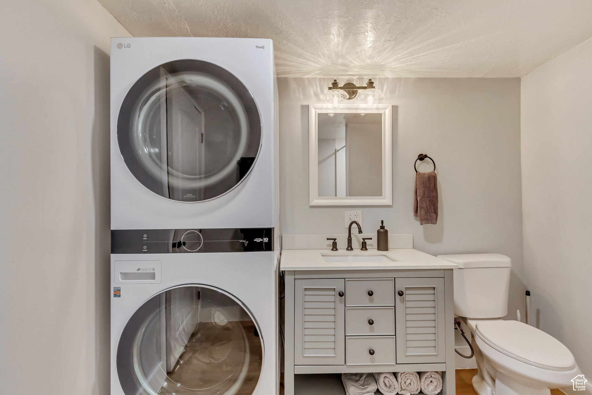 Bathroom featuring vanity, stacked washer / dryer, and toilet