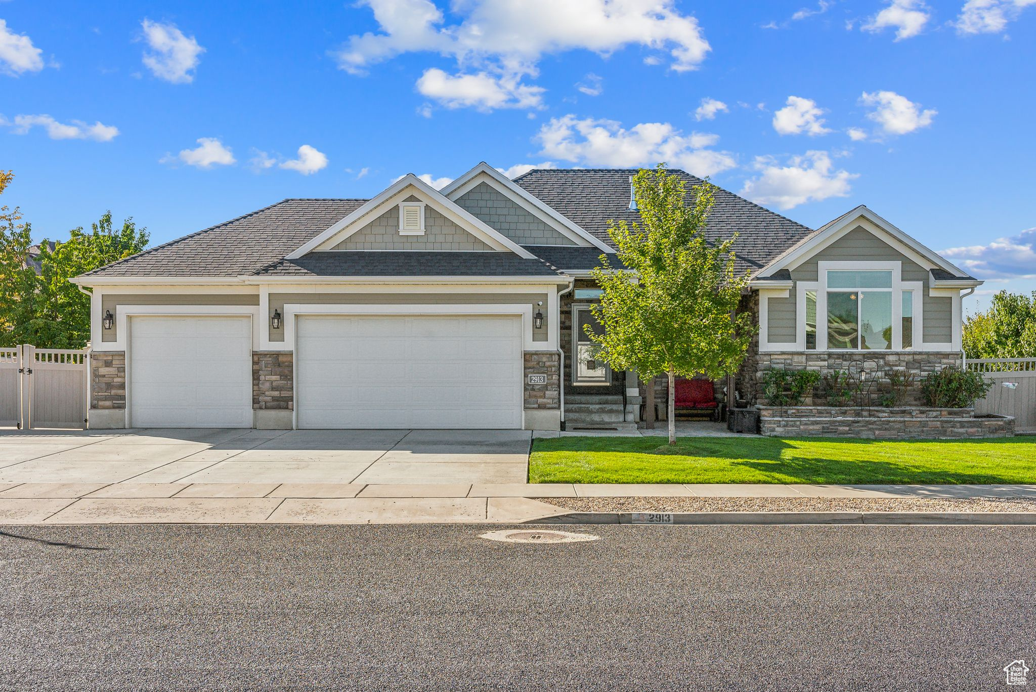 Craftsman inspired home with a front lawn, driveway, stone siding, fence, and a garage