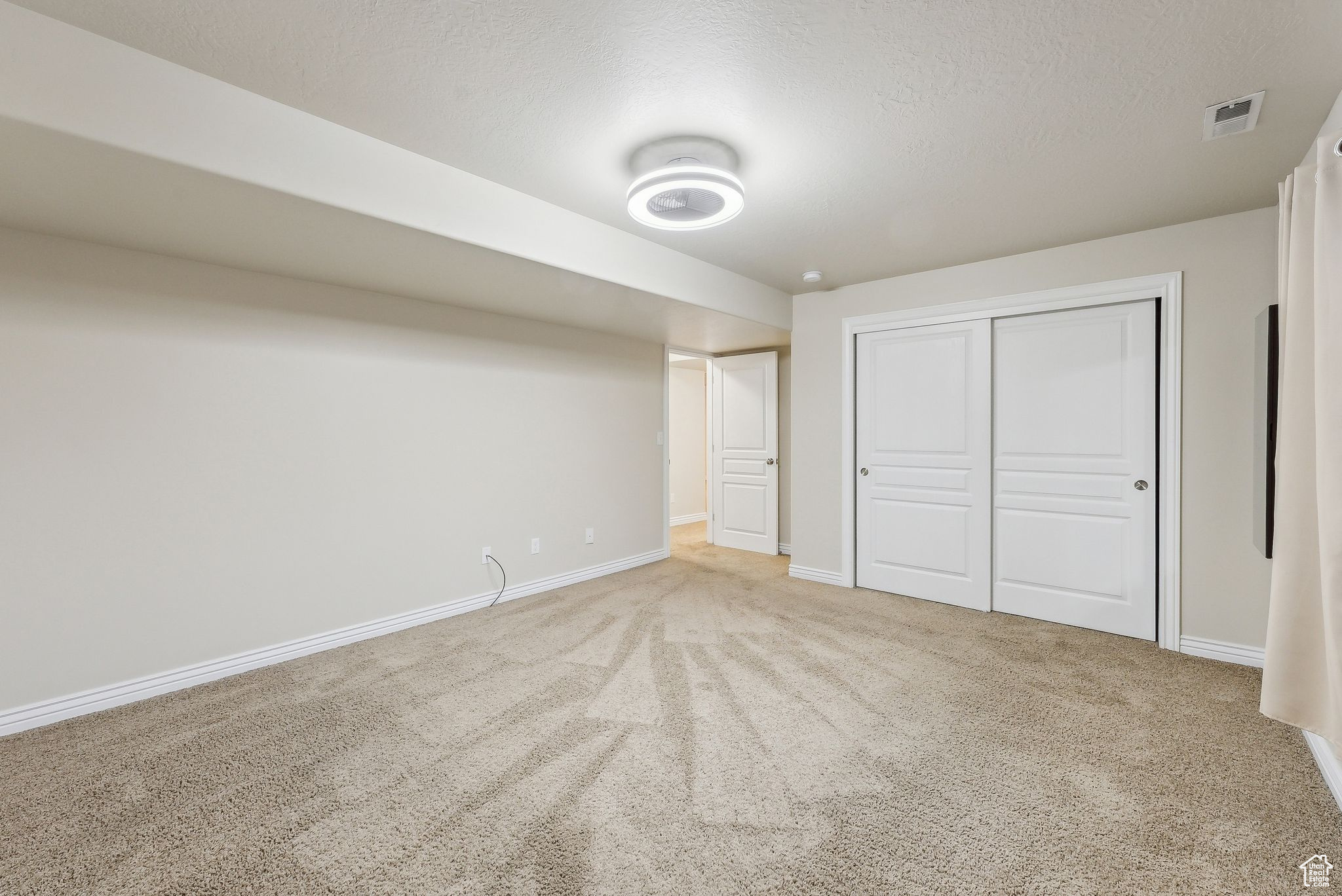 Unfurnished bedroom with visible vents, carpet, baseboards, and a textured ceiling