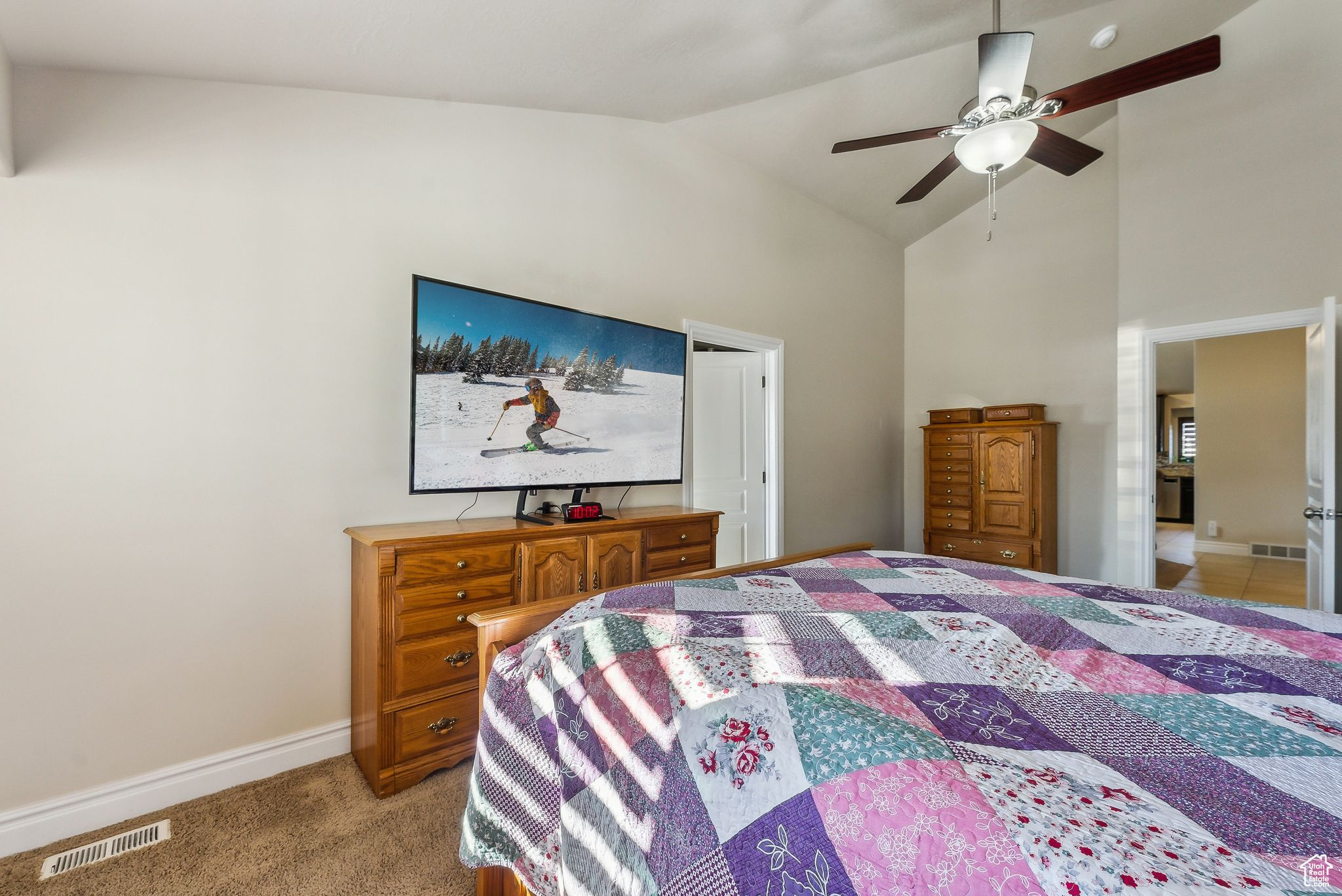 Bedroom with high vaulted ceiling, light colored carpet, visible vents, and baseboards