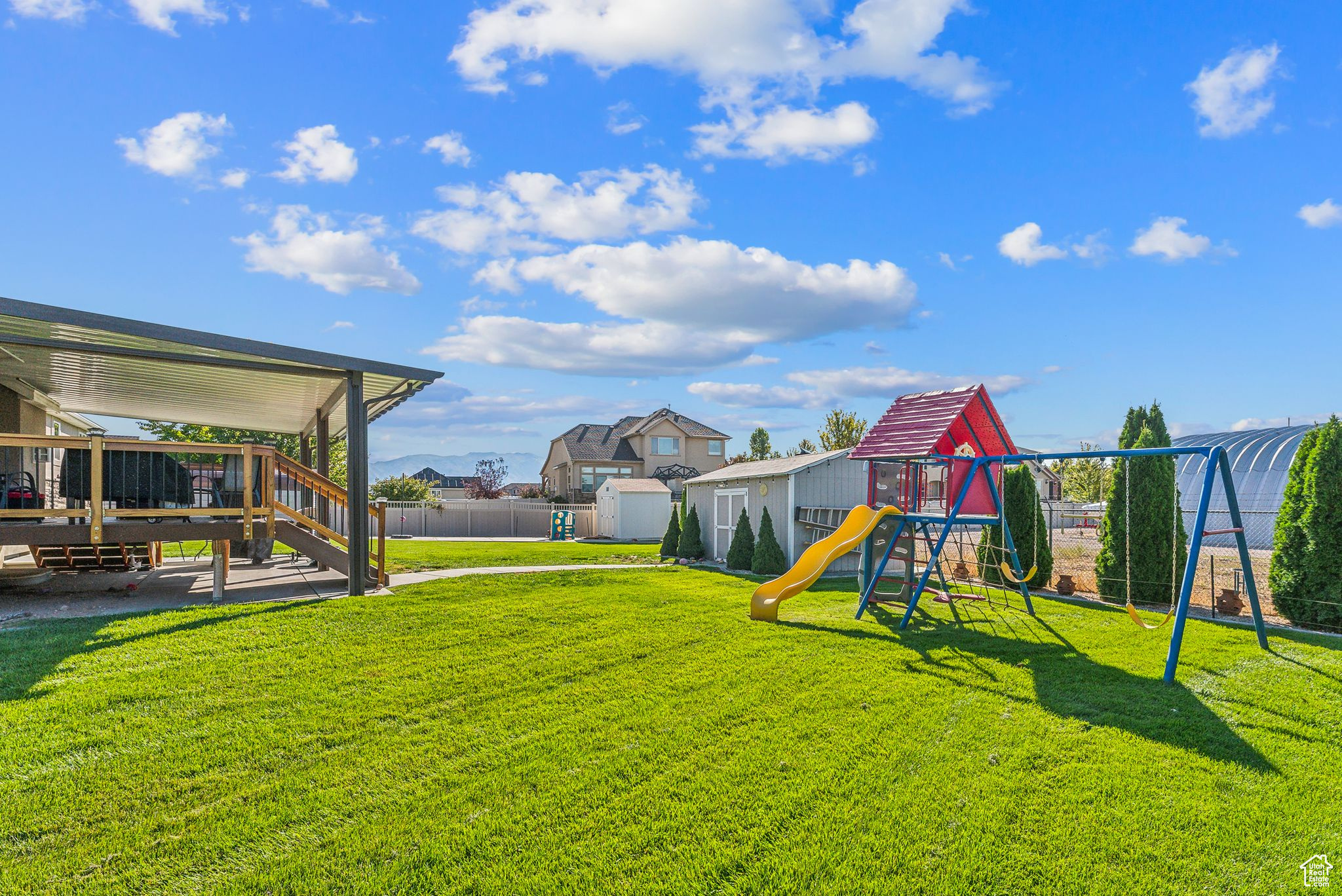View of yard with an outbuilding, fence, a playground, a storage shed, and a wooden deck