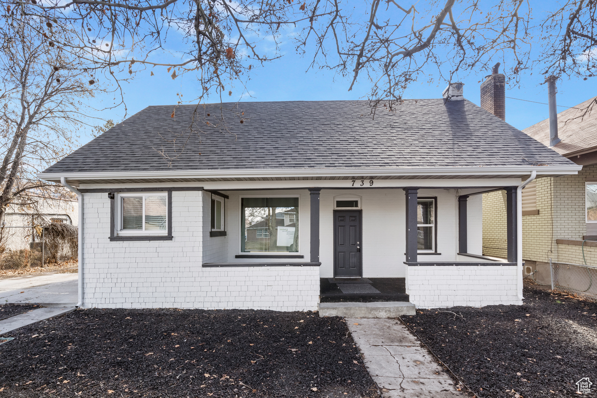 Bungalow featuring a porch, a chimney, brick siding, and a shingled roof