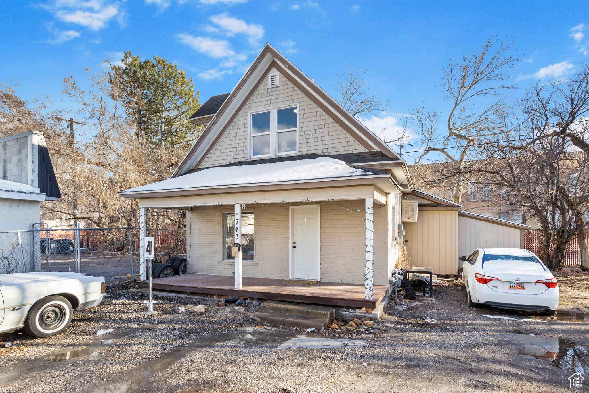 View of front facade featuring a porch, fence, and brick siding