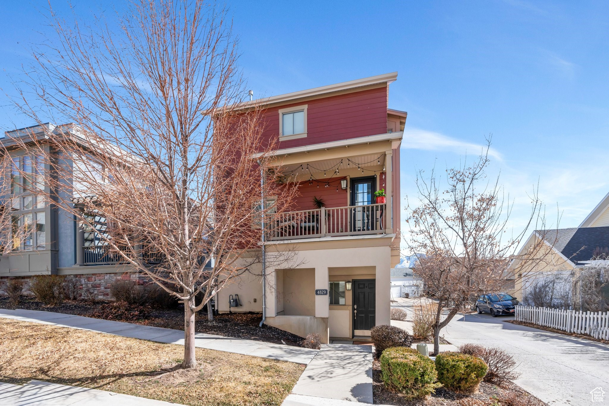 View of front of home with stucco siding, a balcony, and fence