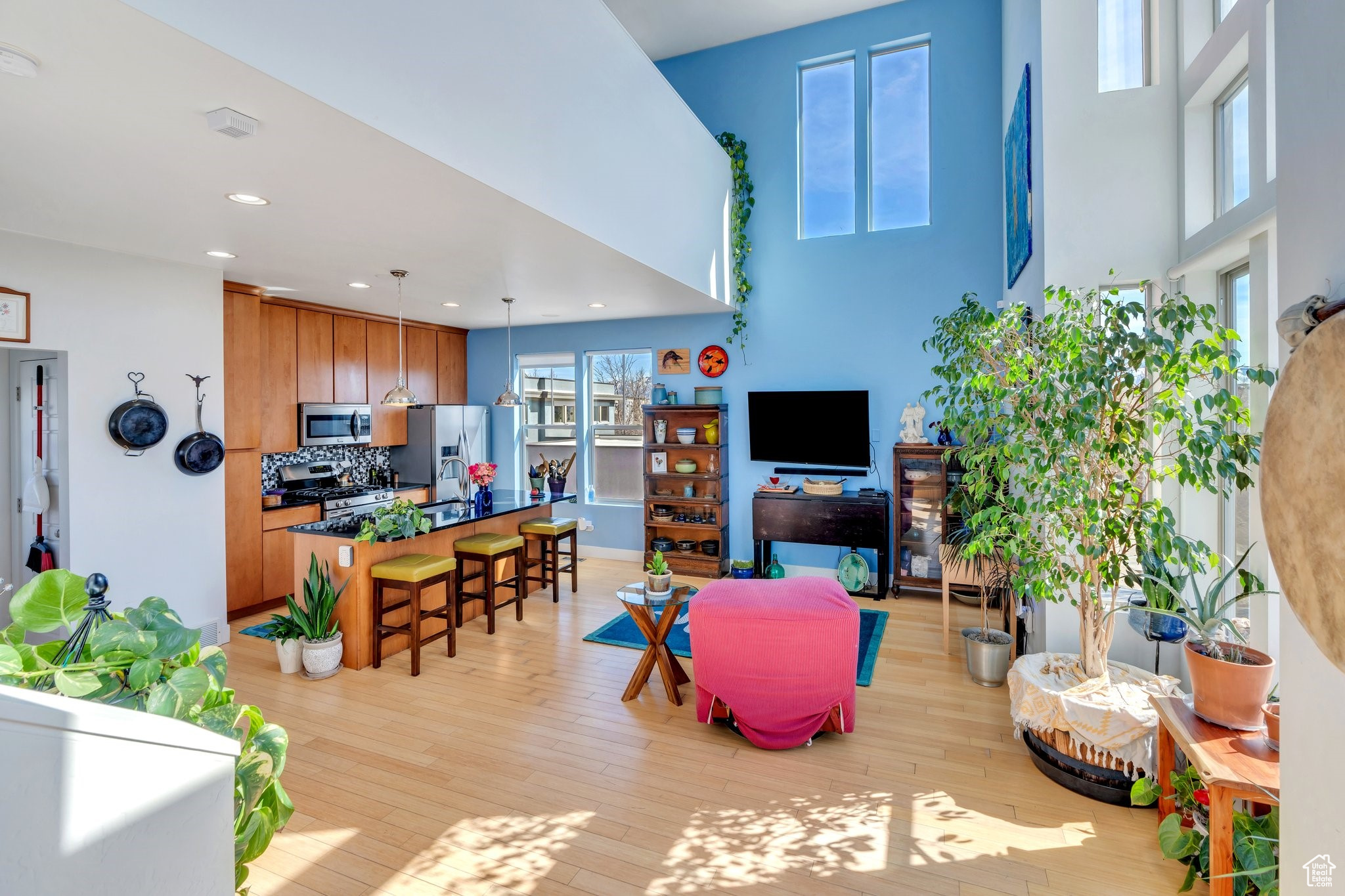 Living area with recessed lighting, baseboards, a high ceiling, and light wood-style flooring