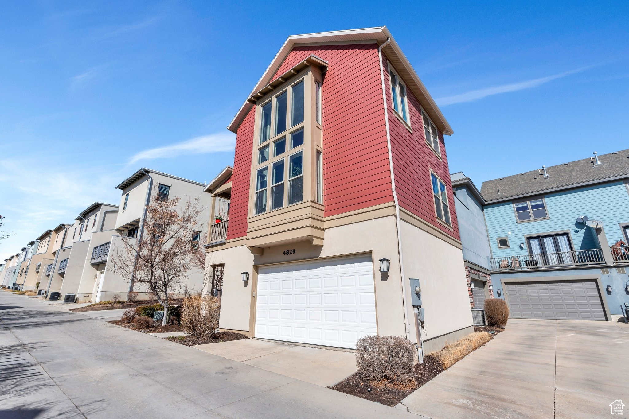 View of front of home featuring a balcony, driveway, an attached garage, stucco siding, and a residential view