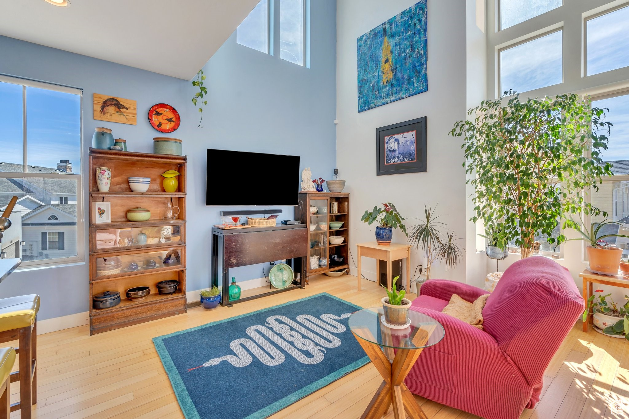 Living area featuring baseboards, wood-type flooring, and a towering ceiling